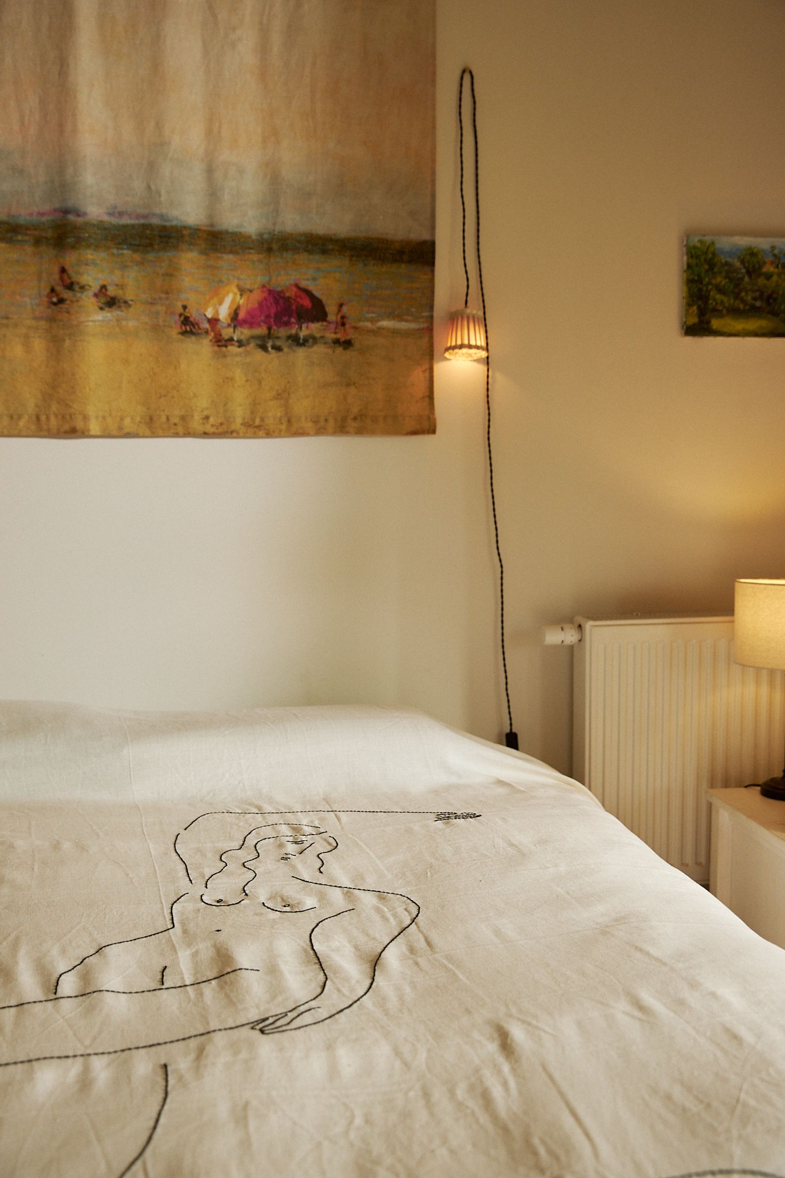 dimly lit bedroom with embroidered bedcover and small lamp