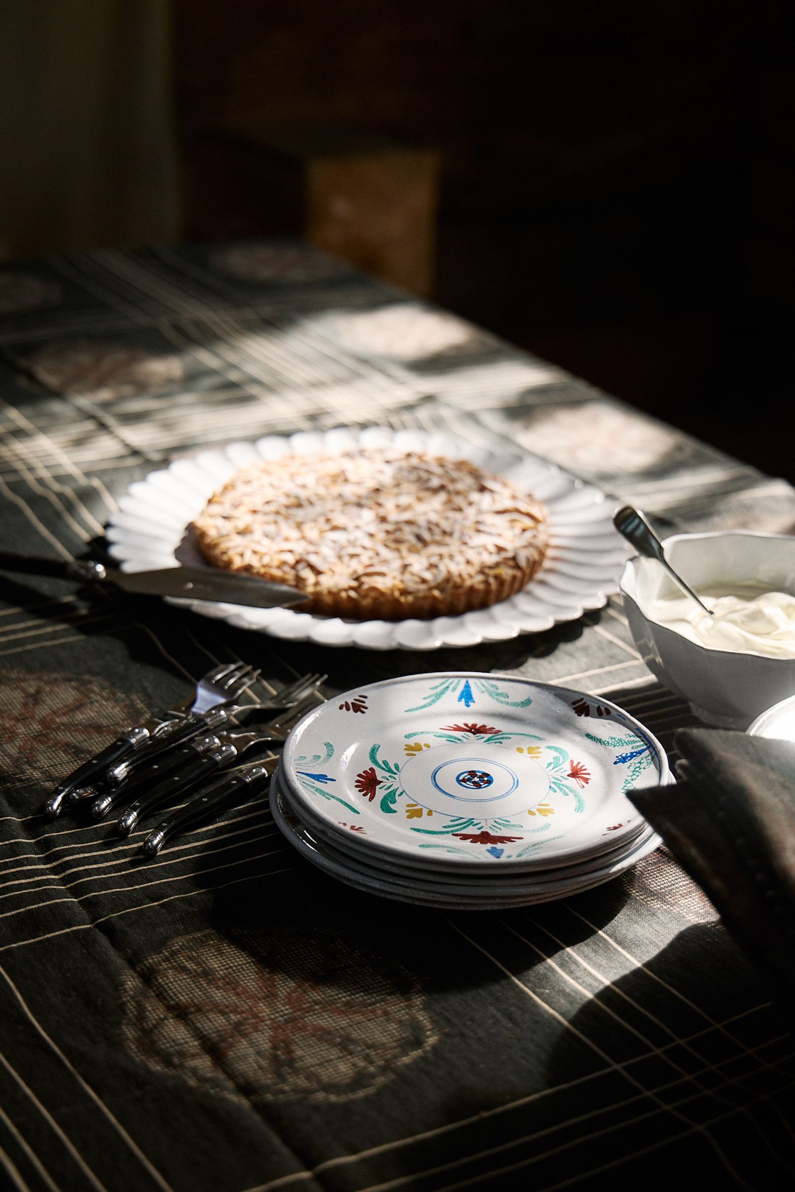 painted ceramic plates, cutlery, cake on platter in the sun