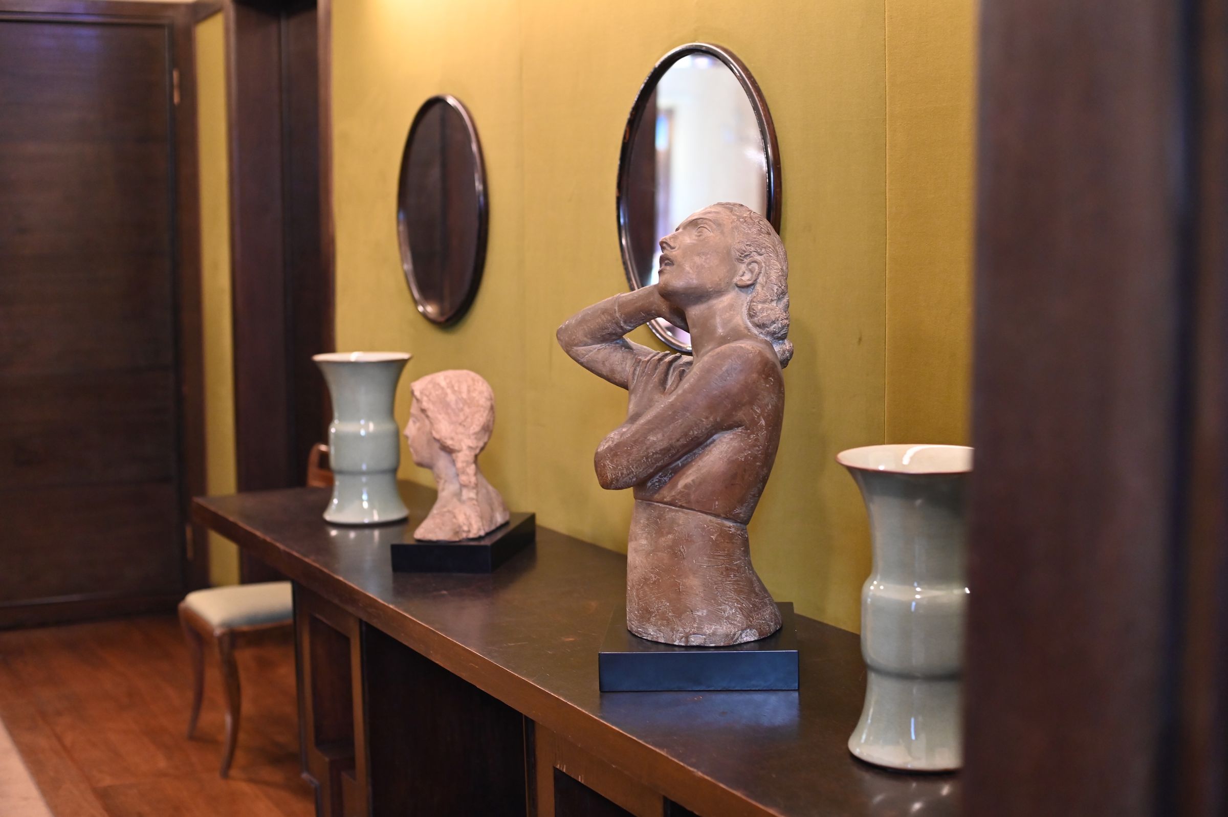 two stone statues in the powder room placed next to the round mirrors