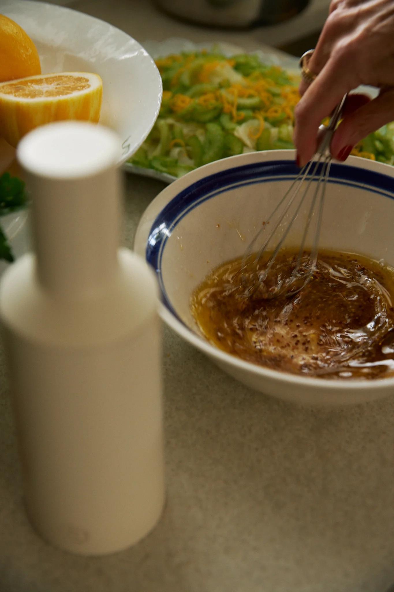 close up of hands whisking the salad dressing in a bowl