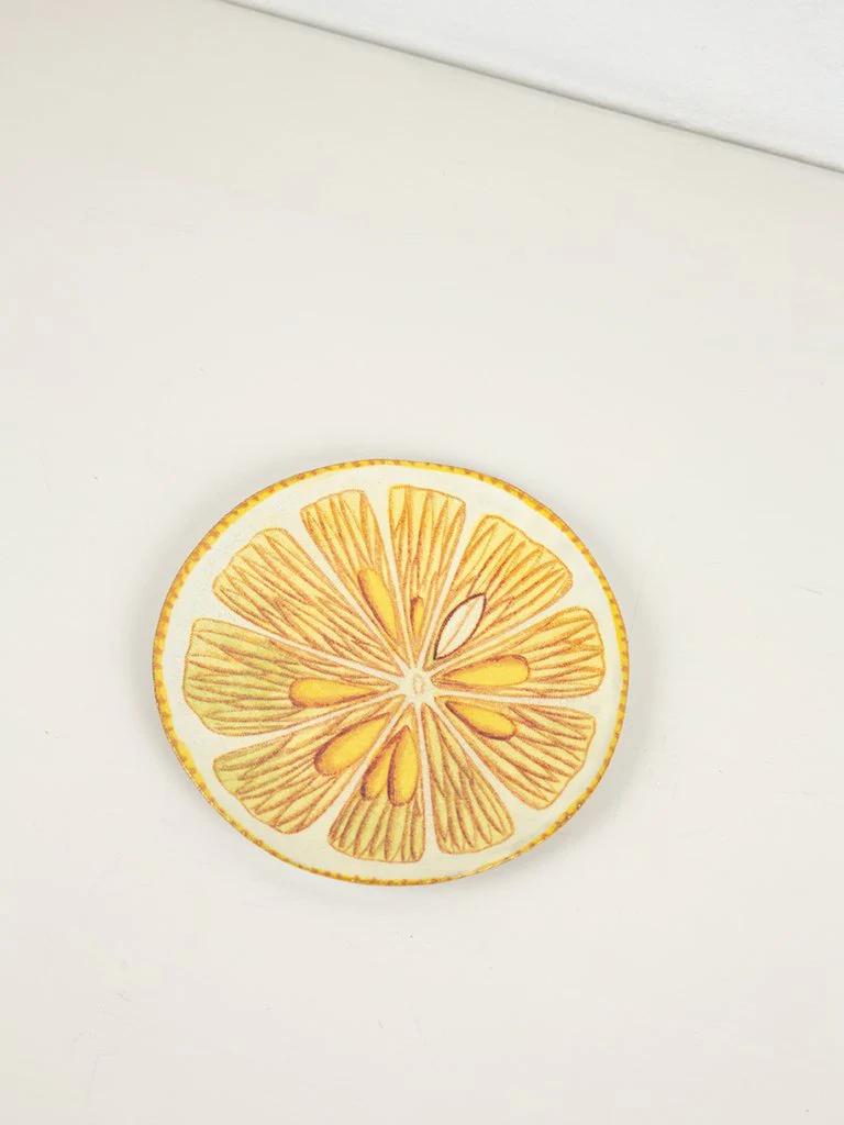 Artistic citrus slice coaster on white surface. Detailed yellow and orange segments evoke summer drinks and celebrations.