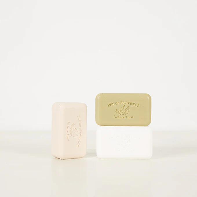 Three Pré de Provence soap bars in pink, green, and white. Embossed with French text and emblem. Suitable for display in Astier de Villatte ceramic dishes.