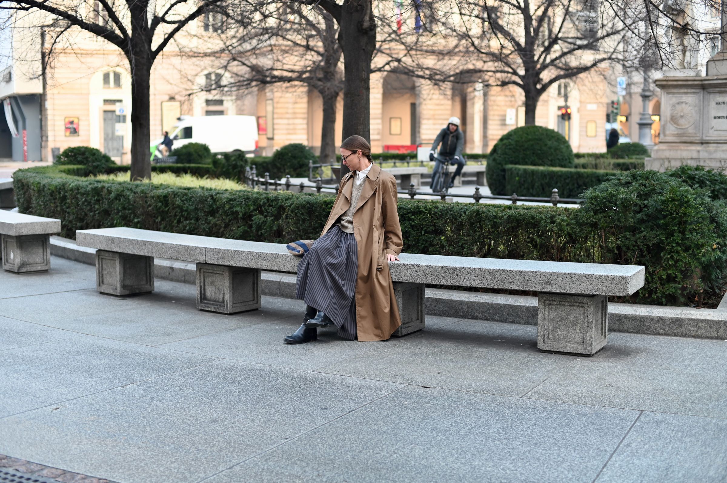 woman sitting on stone bench in Milan square early morning