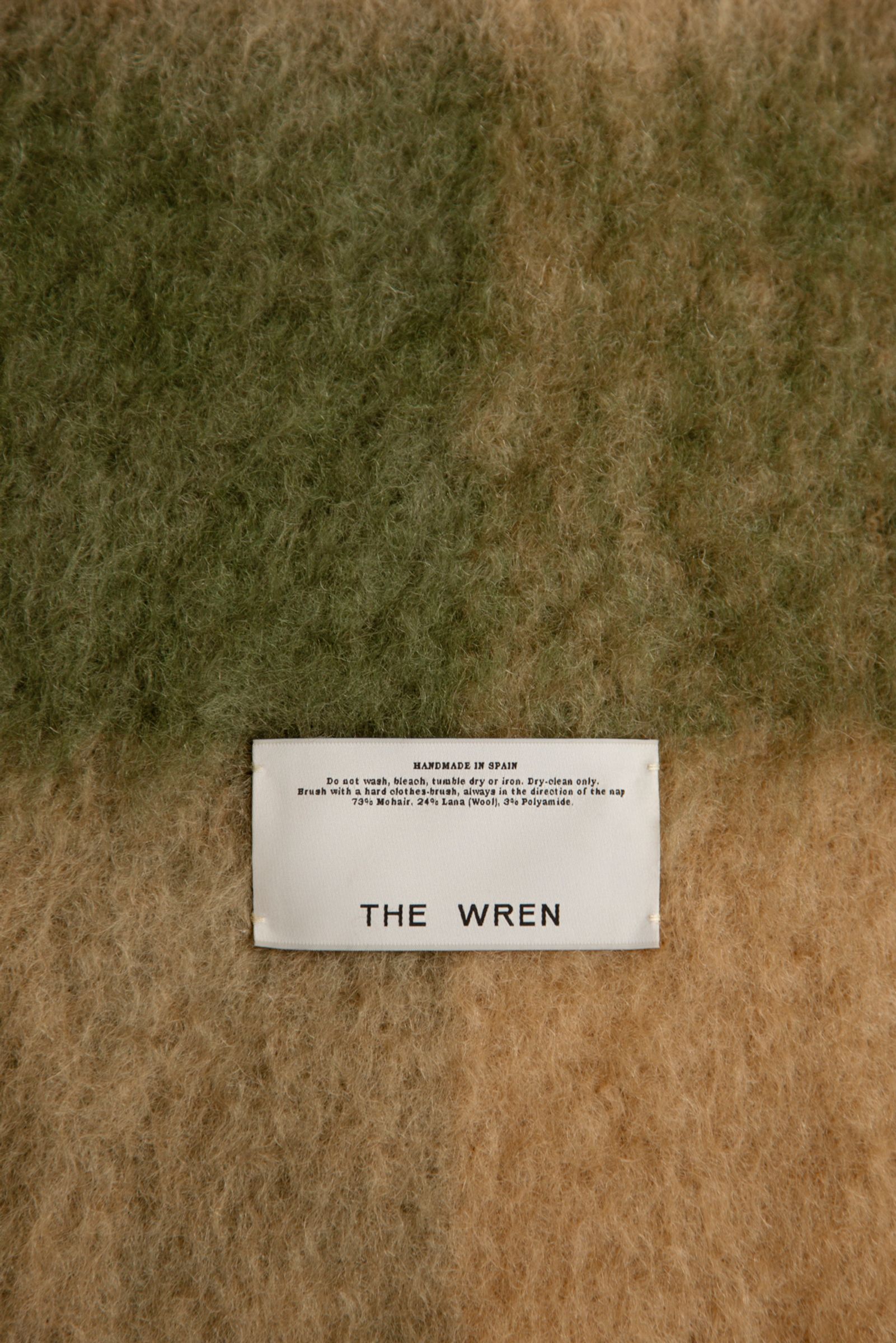 a label is sewn into a green and brown mohair blanket