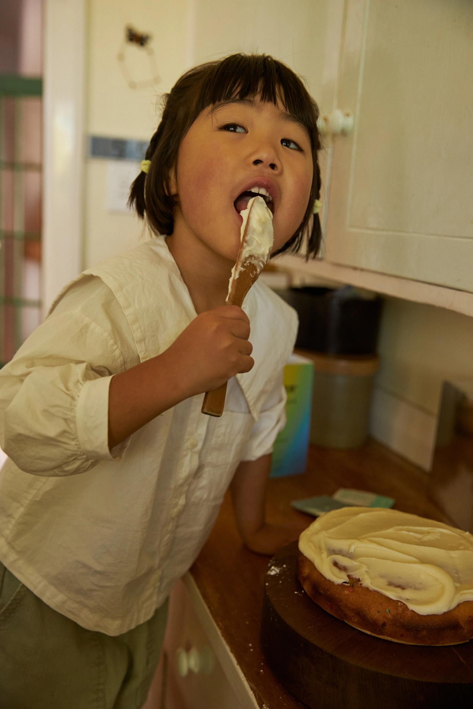 Eden licks the wooden spoon with icing