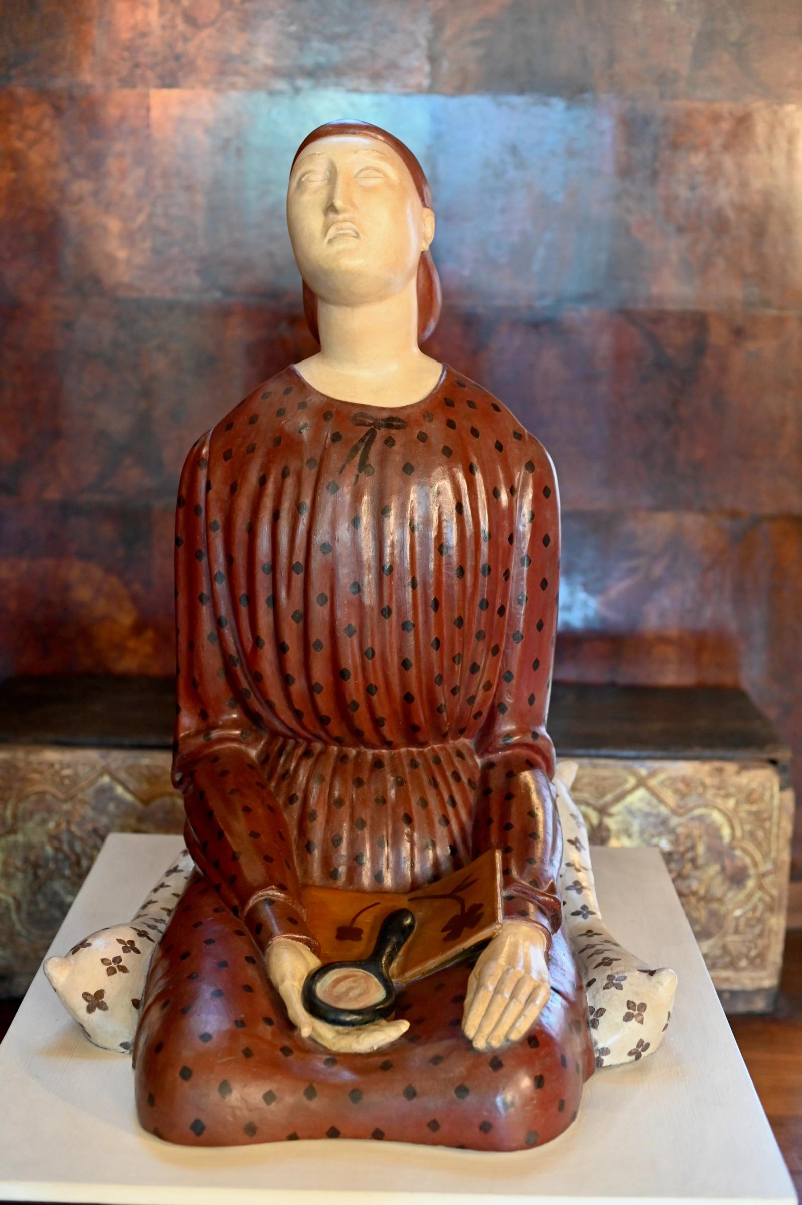 a plaster statue of a woman holding a mirror in a polka dot dress
