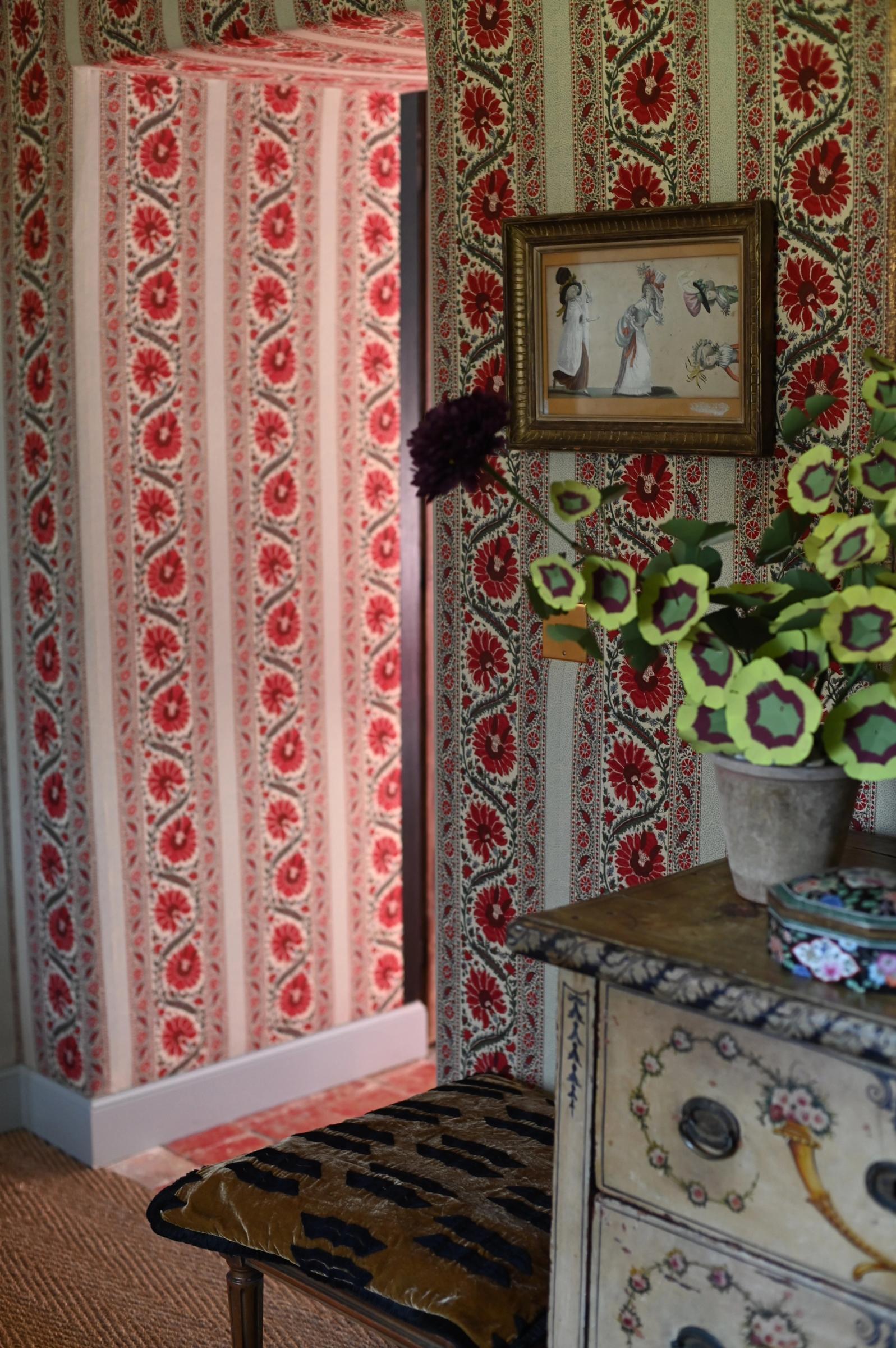 a bedroom lined in red floral fabric walls