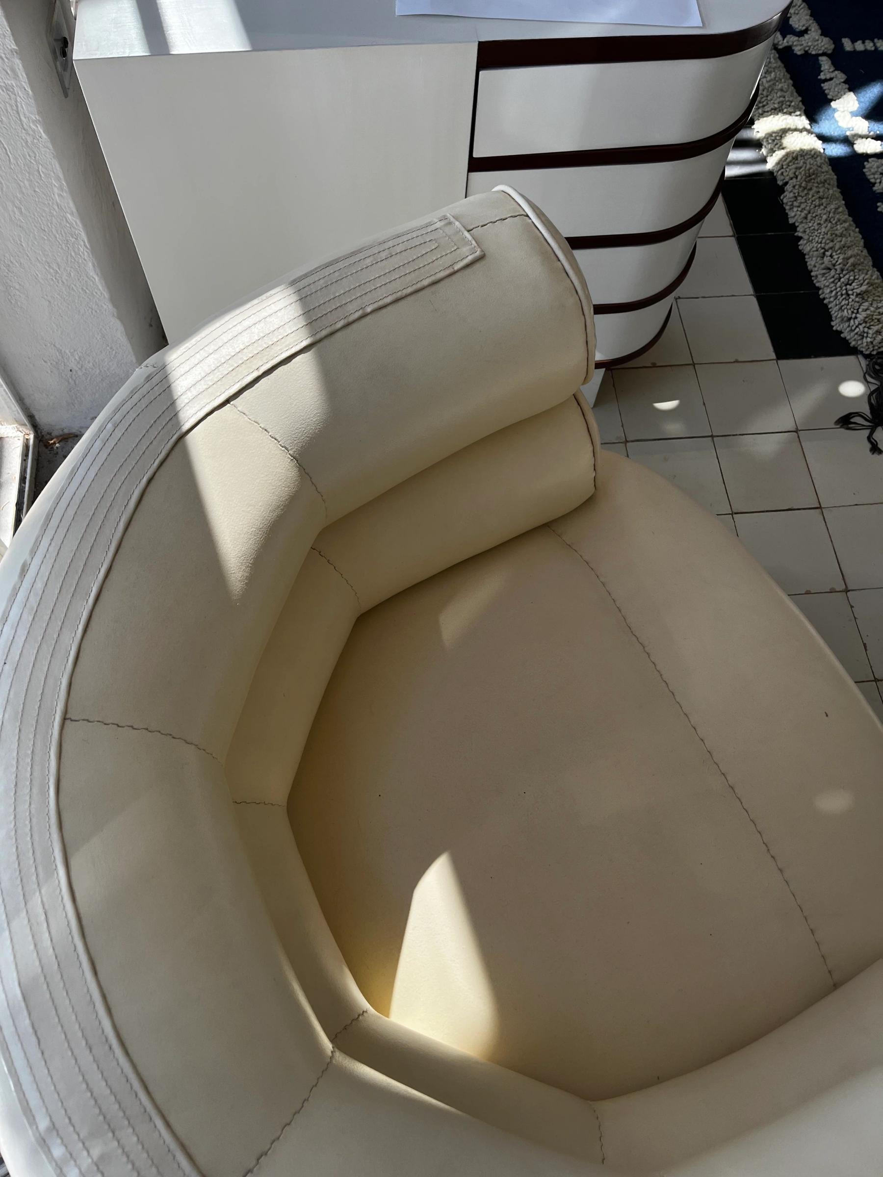 Top-down view of cream-coloured leather chair near white dresser. Tiled flooring and patterned rug partially visible.