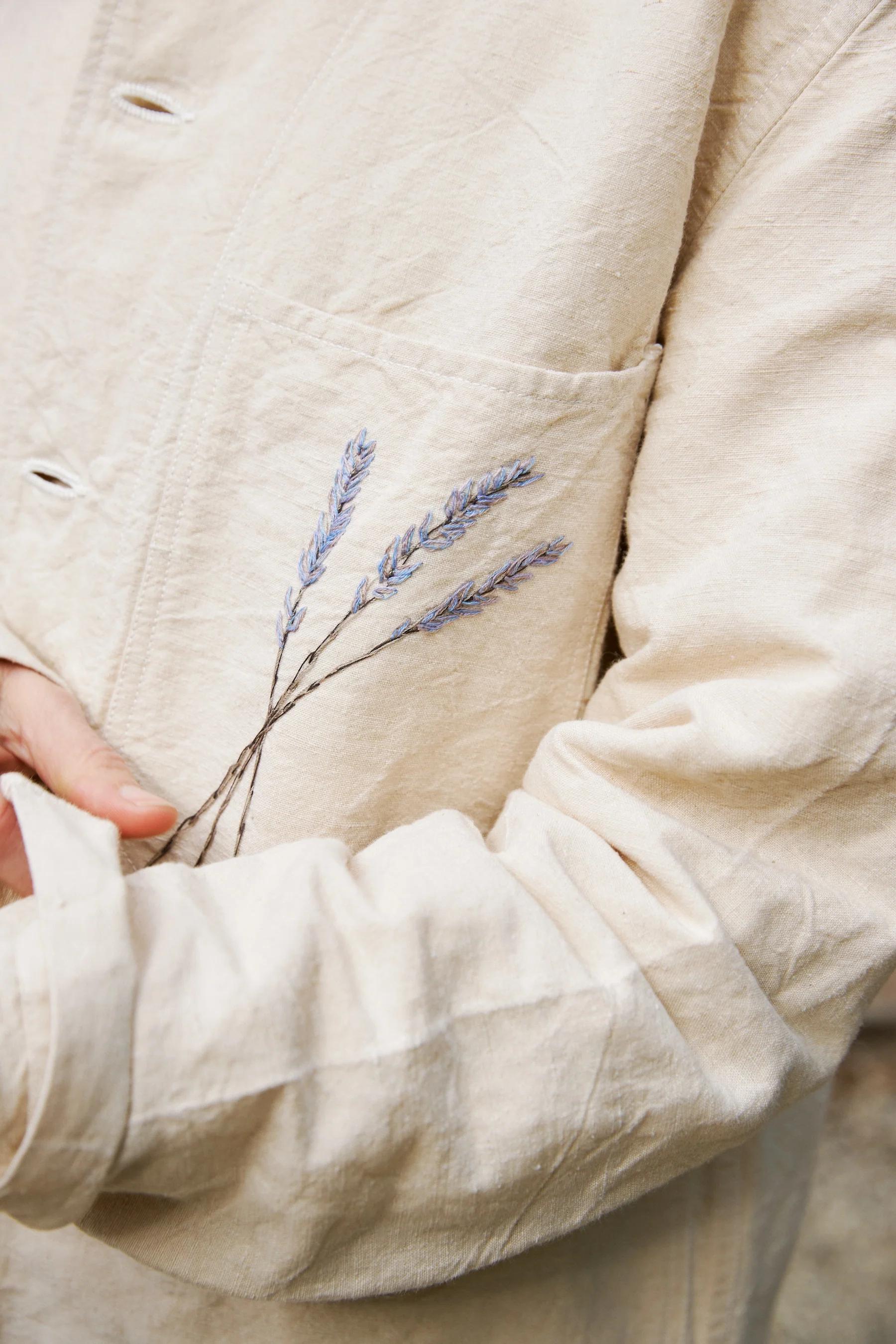 Close up of hand embroidered purple lavender motif of jacket pocket. 