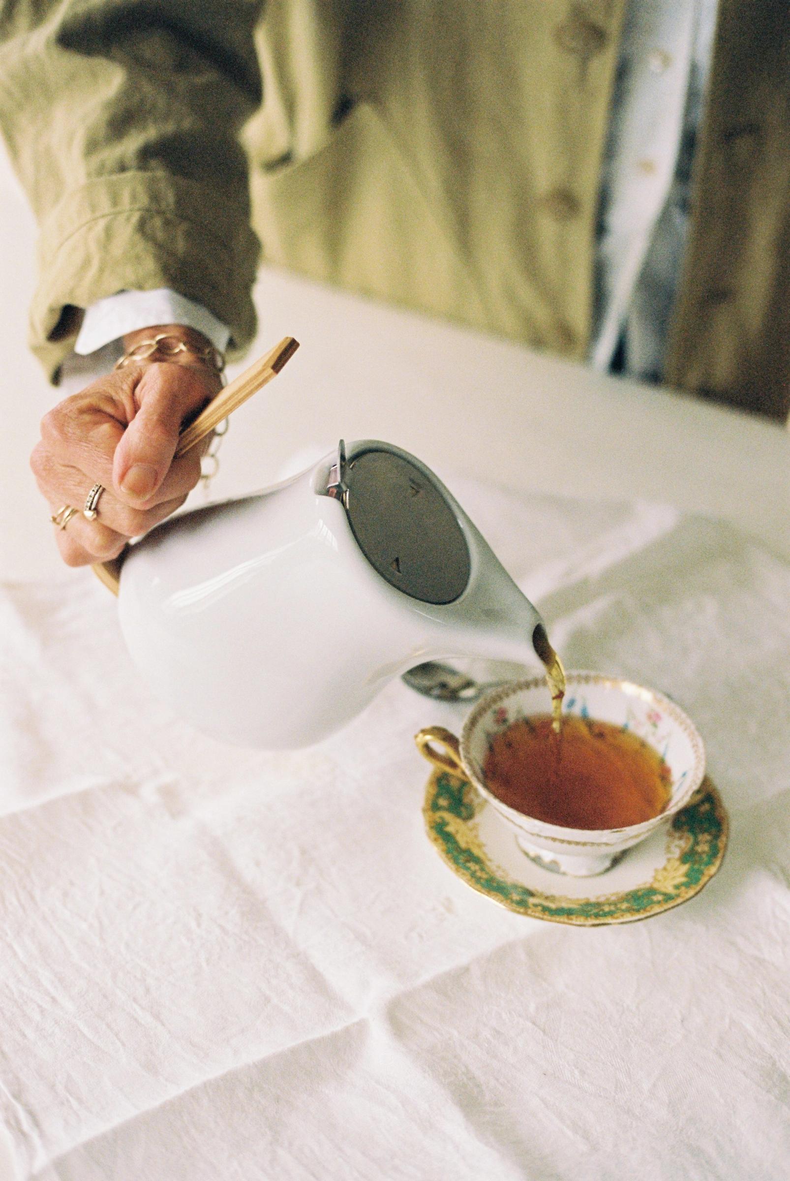 tea pot being poured into antique china tea cup