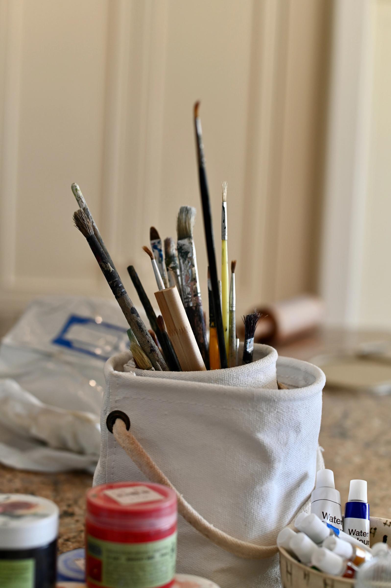 close up of basket of paint brushes and water colour paint tubes