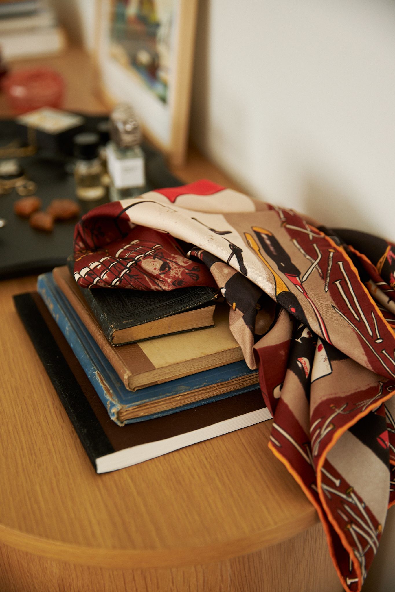 a deep burgundy scarf is strewn across a pile of favourite books