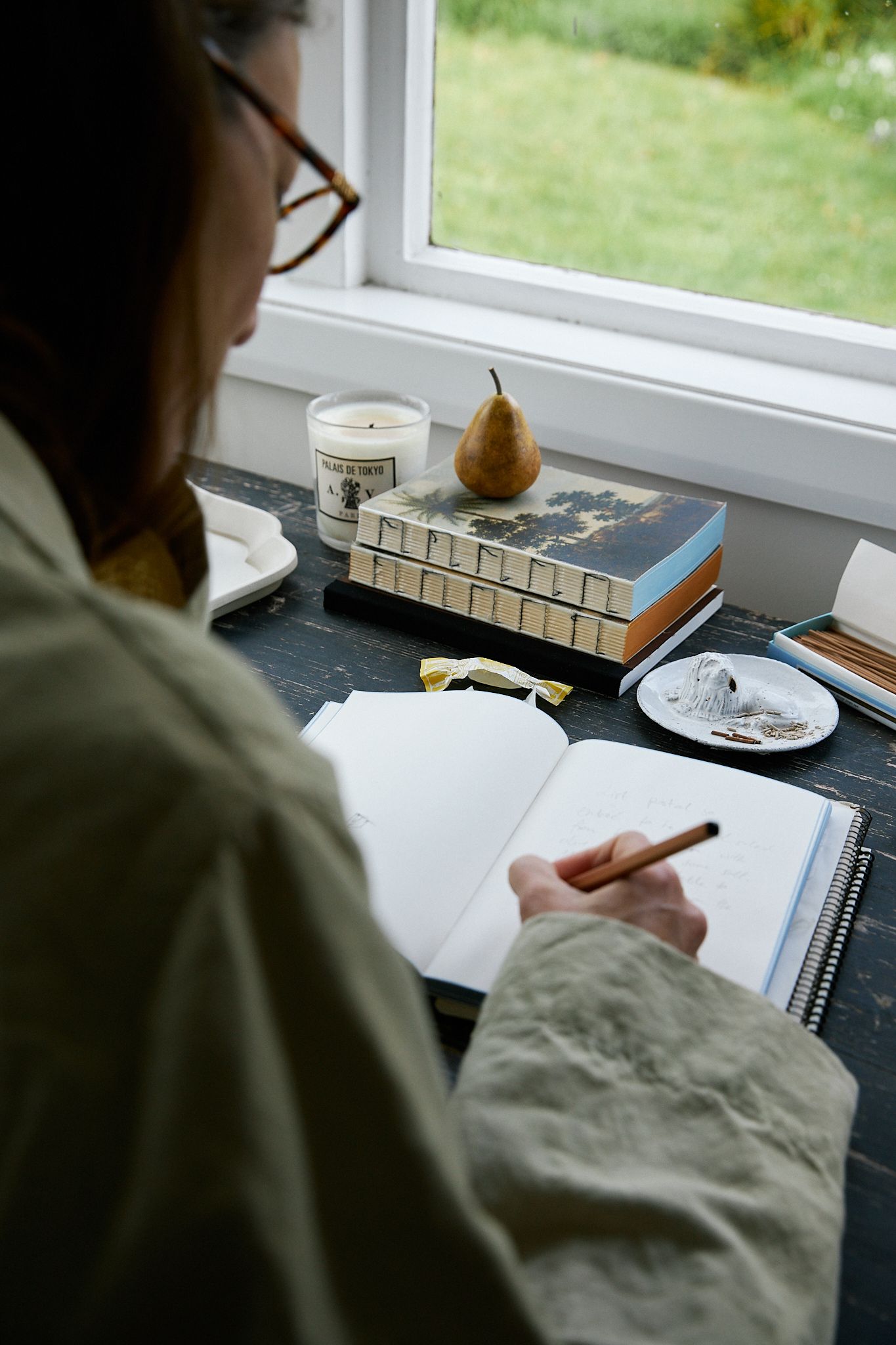 A view over the shoulder of a woman writing a thank you card to a friend