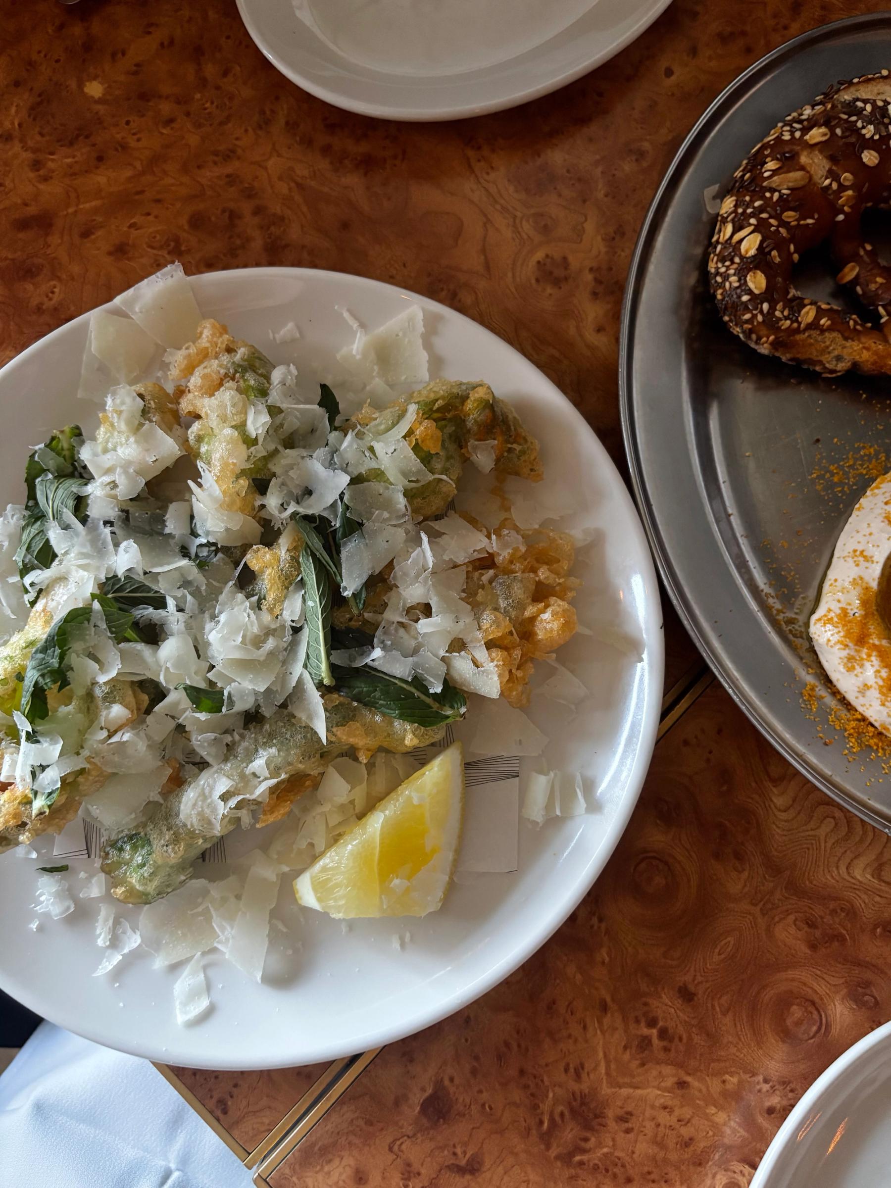 a plate of friend zucchini flowers with shavings of parmesan over top