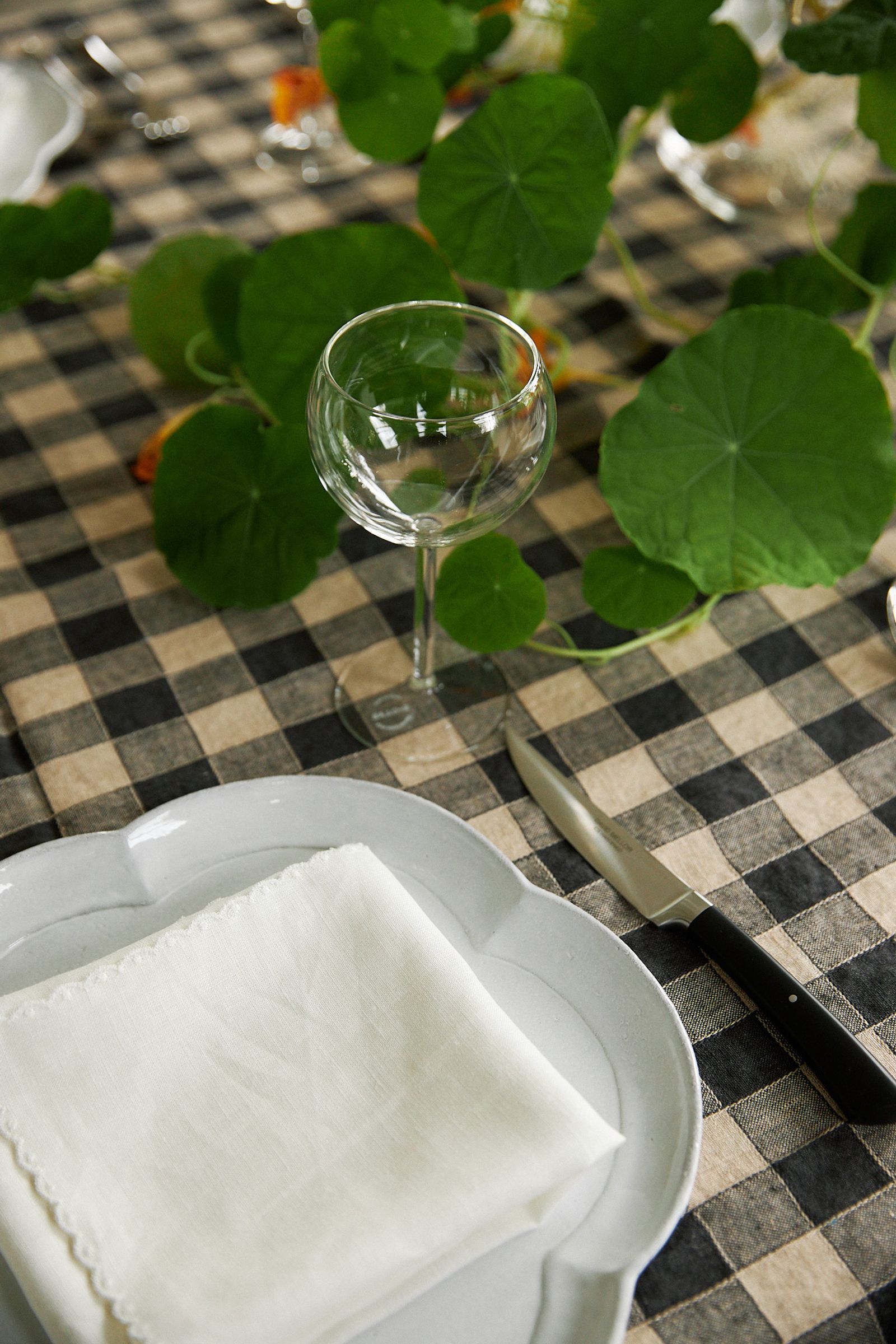 wine glass on gingham tablecloth next to white dinner plate