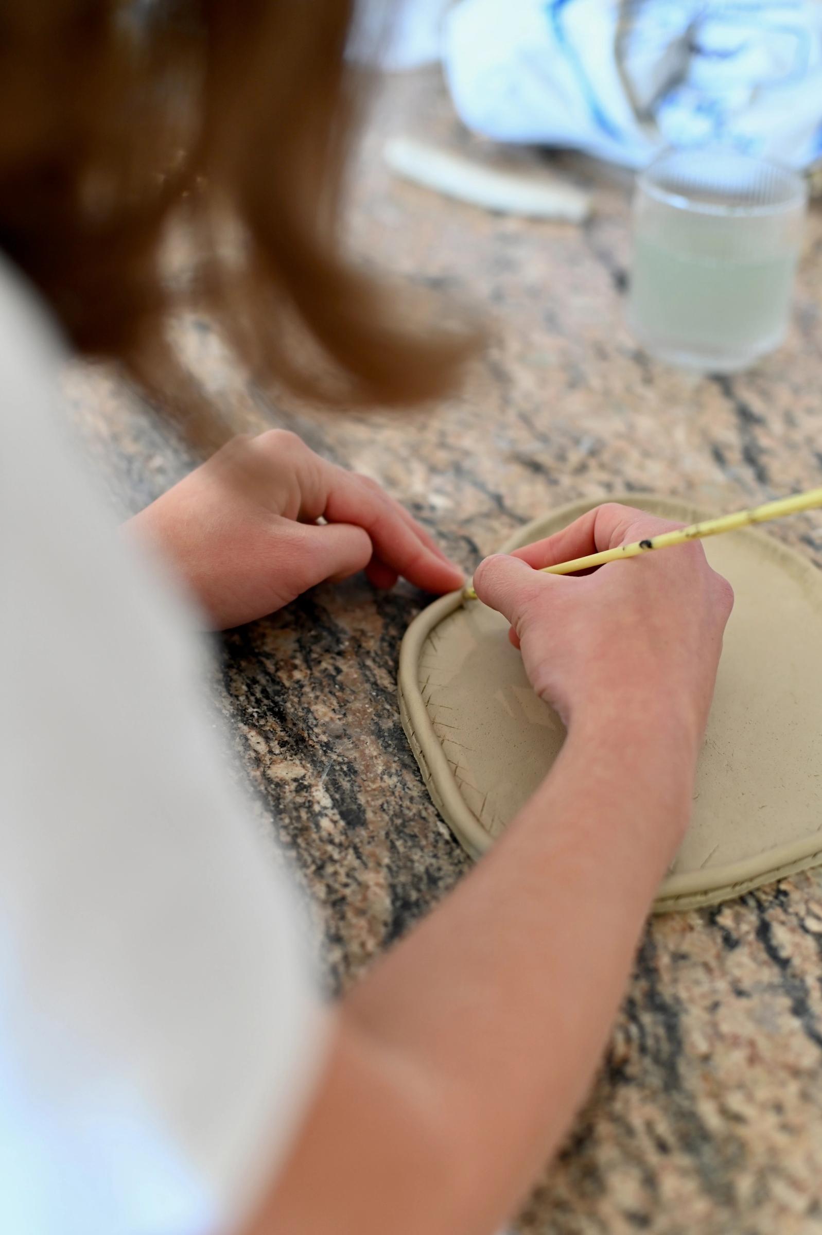 a look over the shoulder of artist working on a ceramic platter