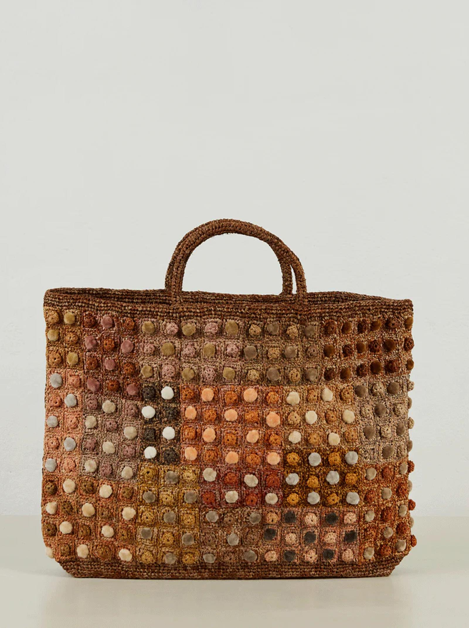 Rectangular woven tote with grid pattern in earthy tones. Two small handles at top. Resembles elegant craftsmanship of Sophie Digard's Parisian knitwear designs.