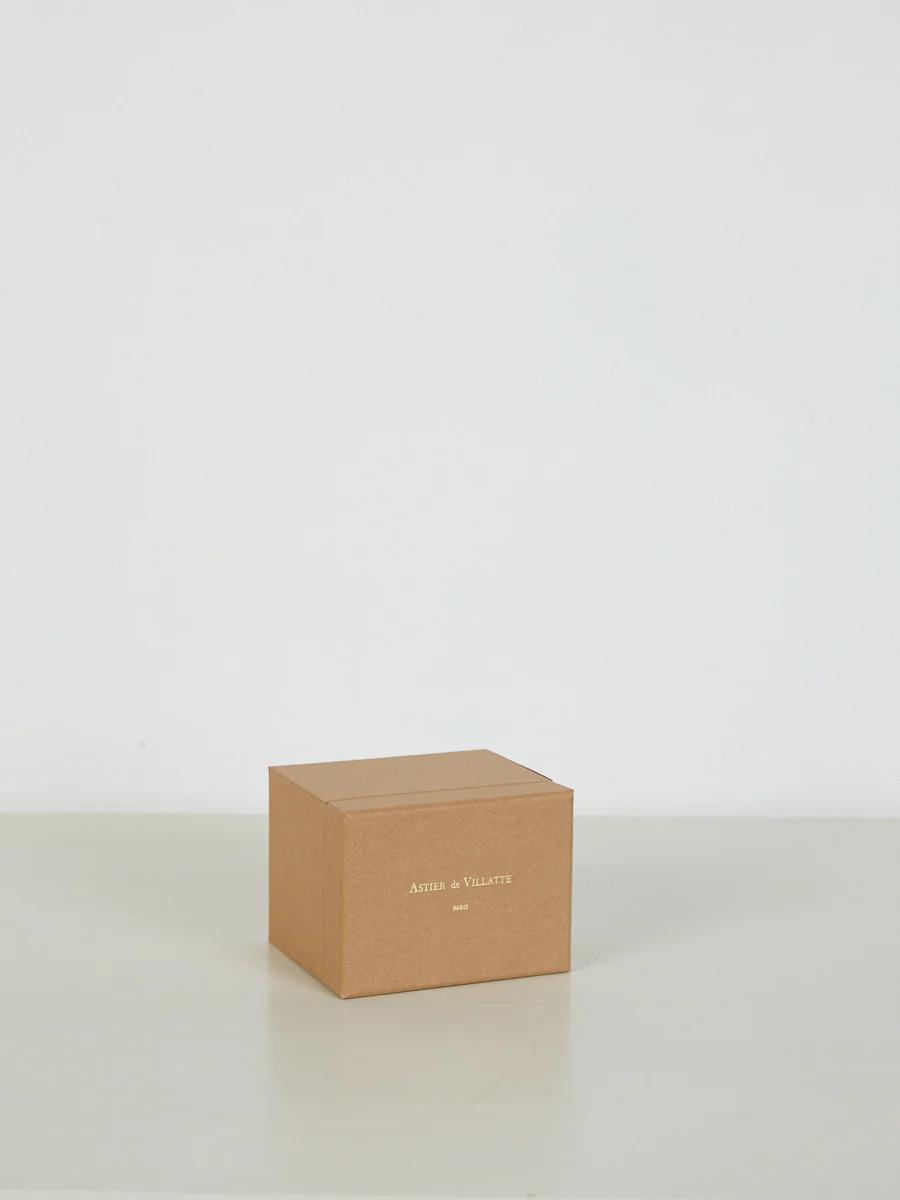 Small brown cardboard box with white "ASTIER de VILLATTE" and "PARIS" text. Light-coloured surface, neutral background.