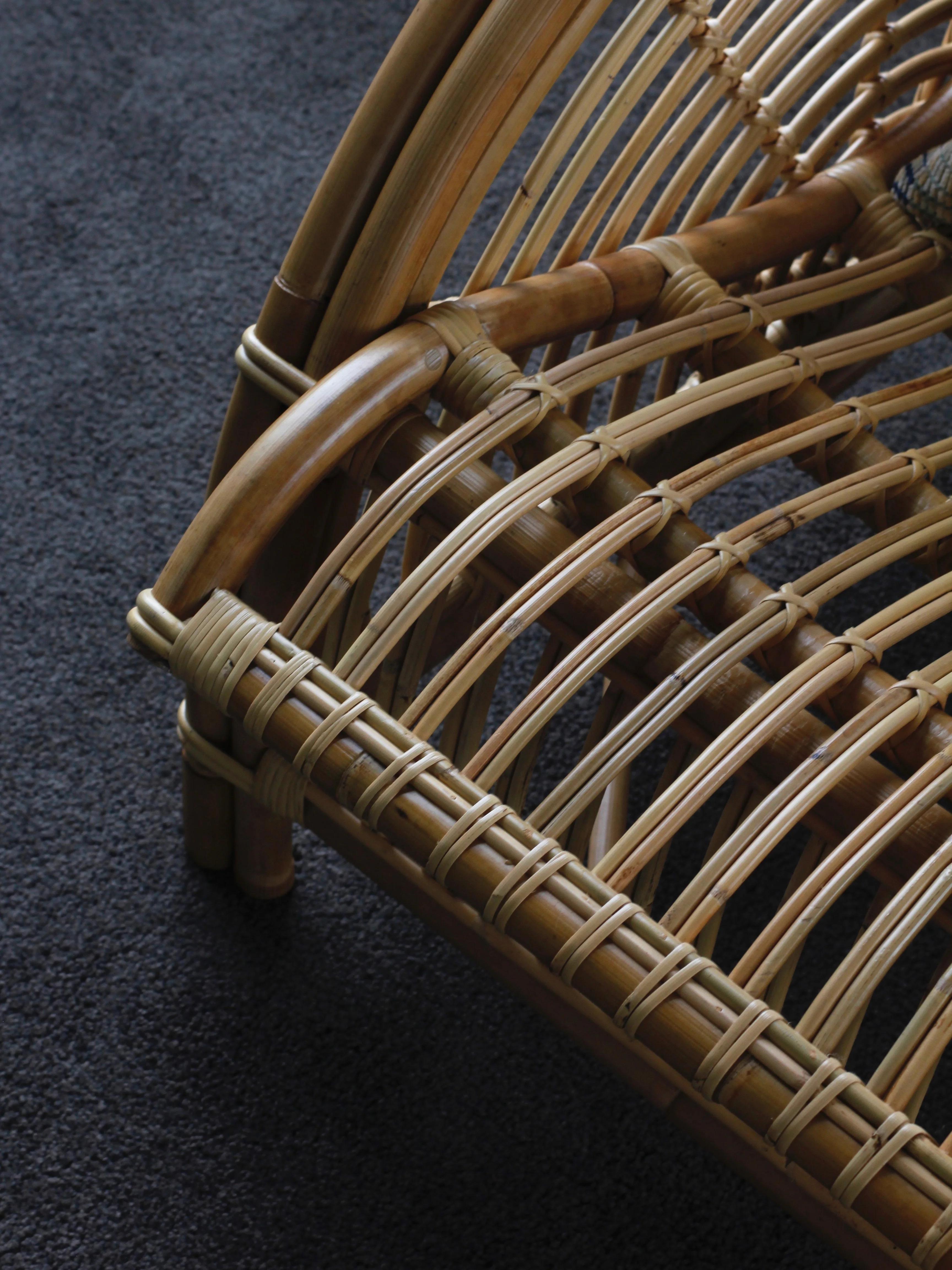 Close-up of a woven rattan chair showcasing intricate detailing and craftsmanship, sitting on a dark carpeted floor.