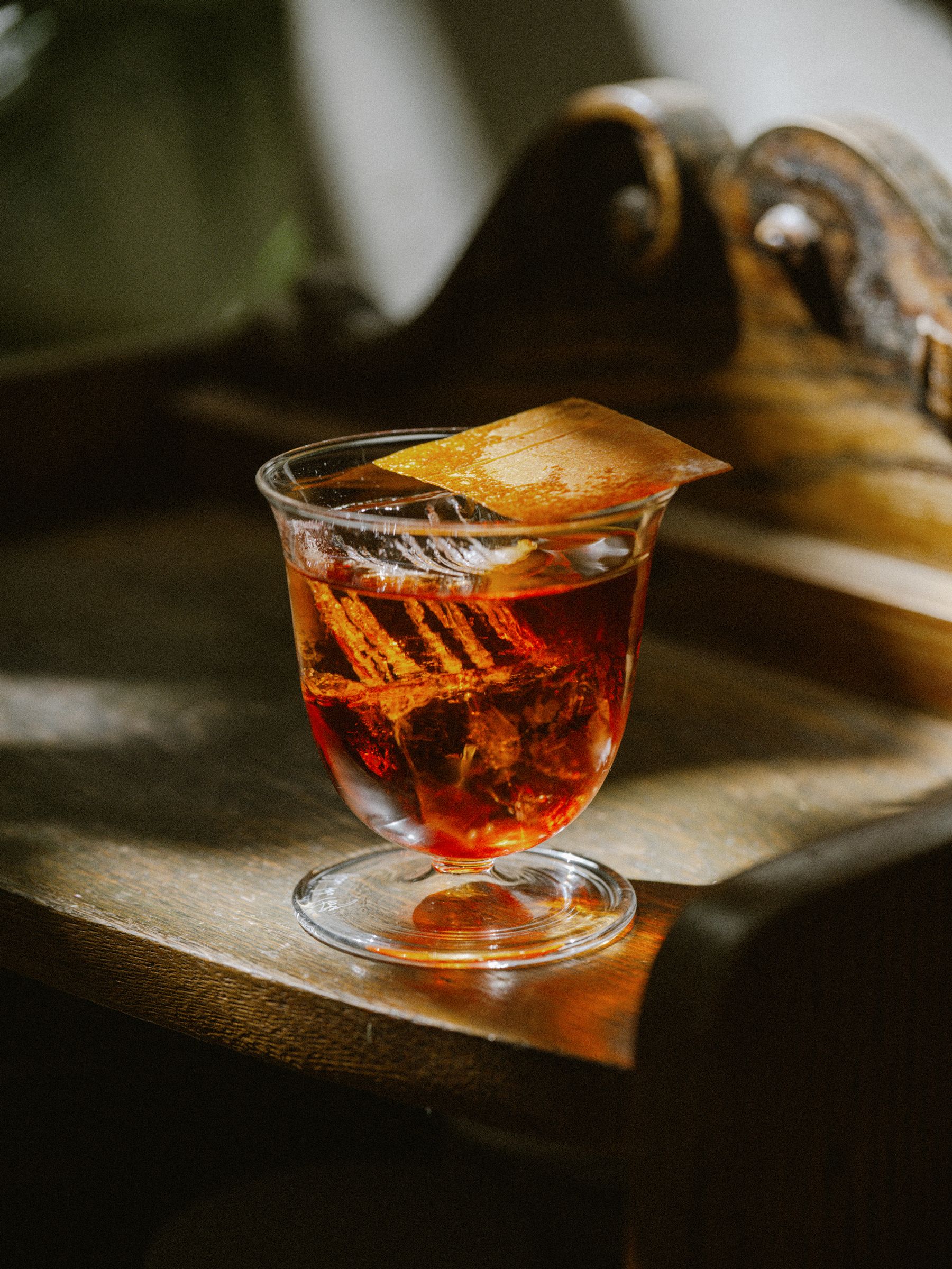 Glass on wooden sideboard filled with a cocktail in natural light 