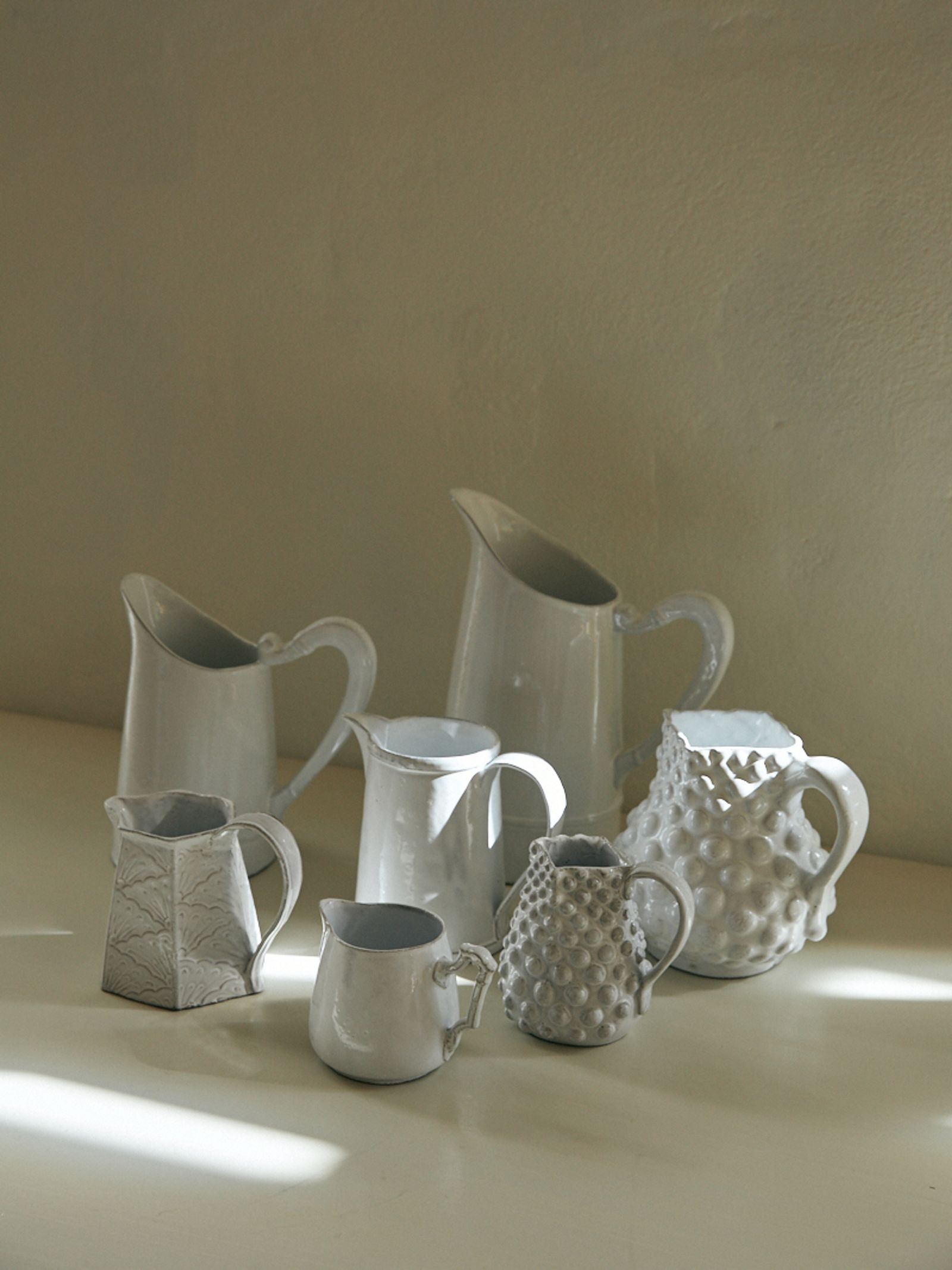 a group of ceramic pitchers on a table top