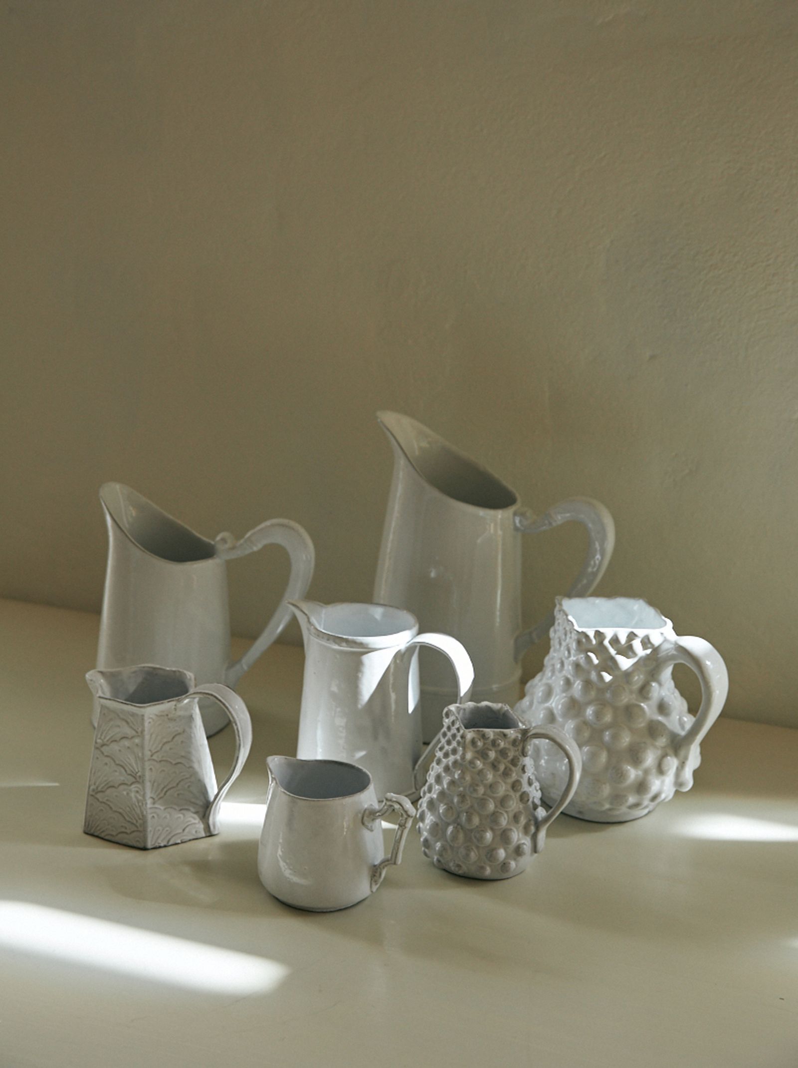 a group of ceramic pitchers on a table top
