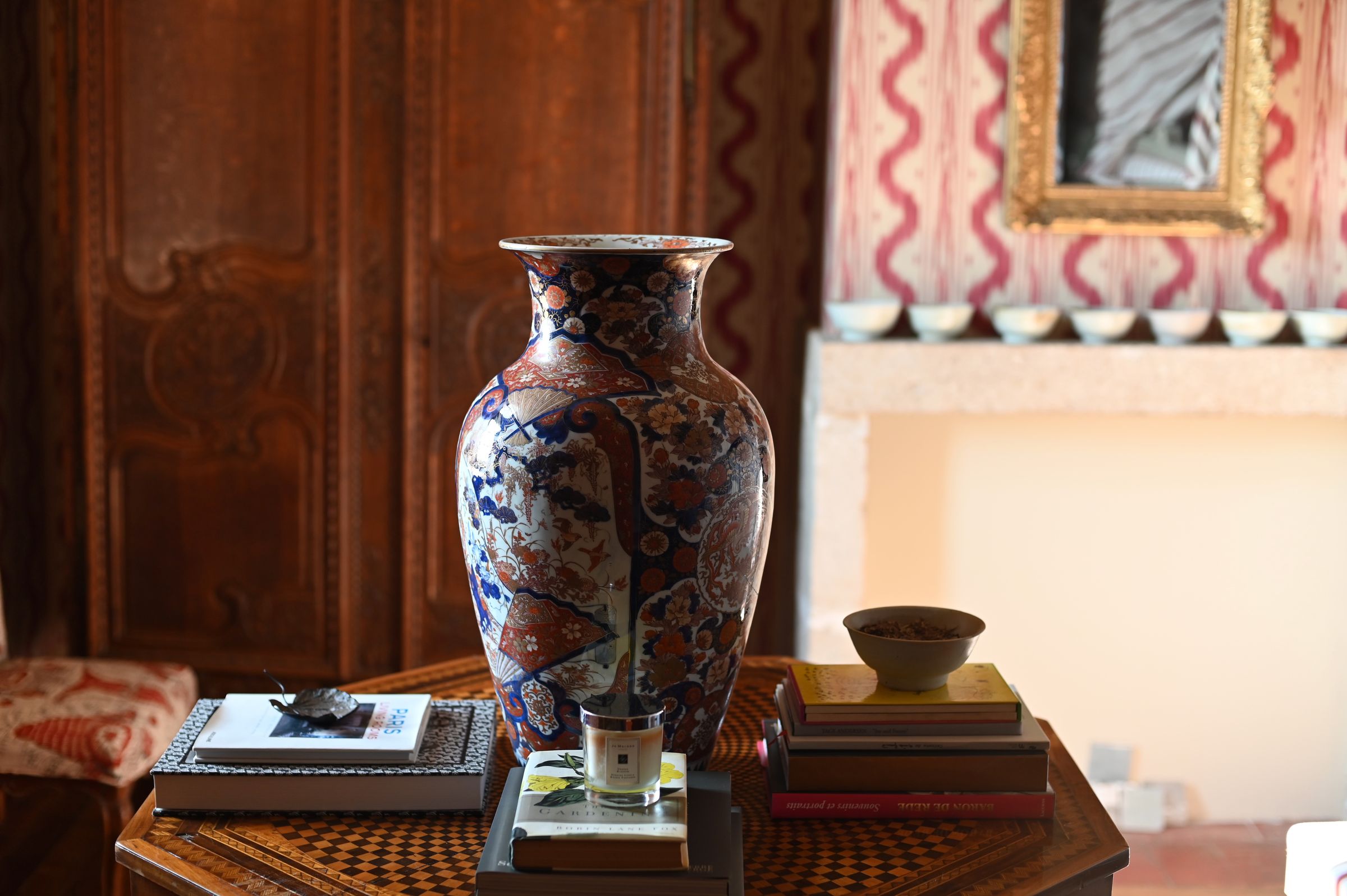 antique vase sits on a pile of books in a bedroom