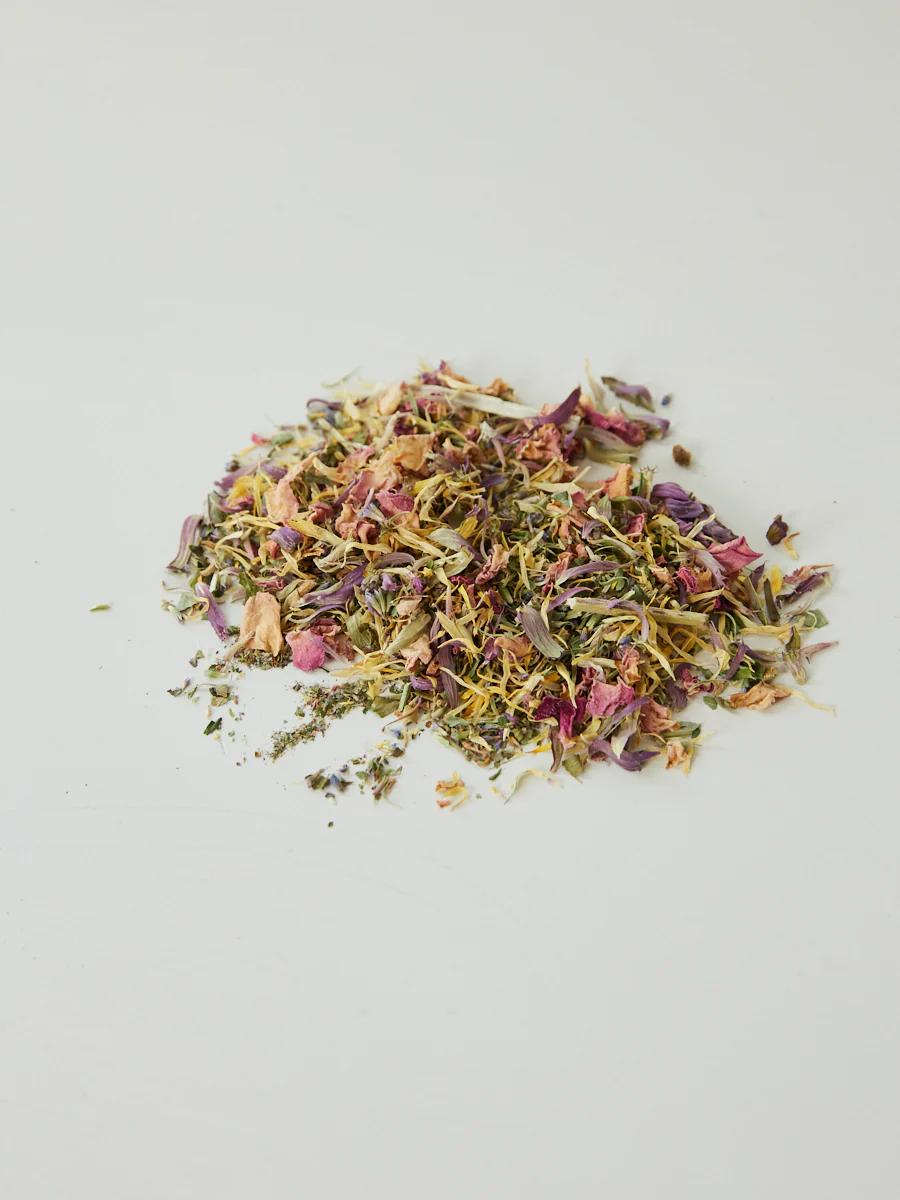 Colourful loose dried herbs, leaves, and flower petals scattered on light surface. Blend of premium small batch teas.