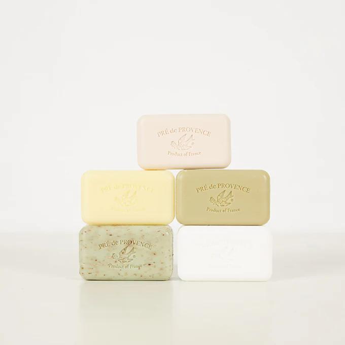 Pyramid stack of five Pré de Provence soap bars. Handmade in Paris. Various beige, white, and green shades with embossed brand name and logo.