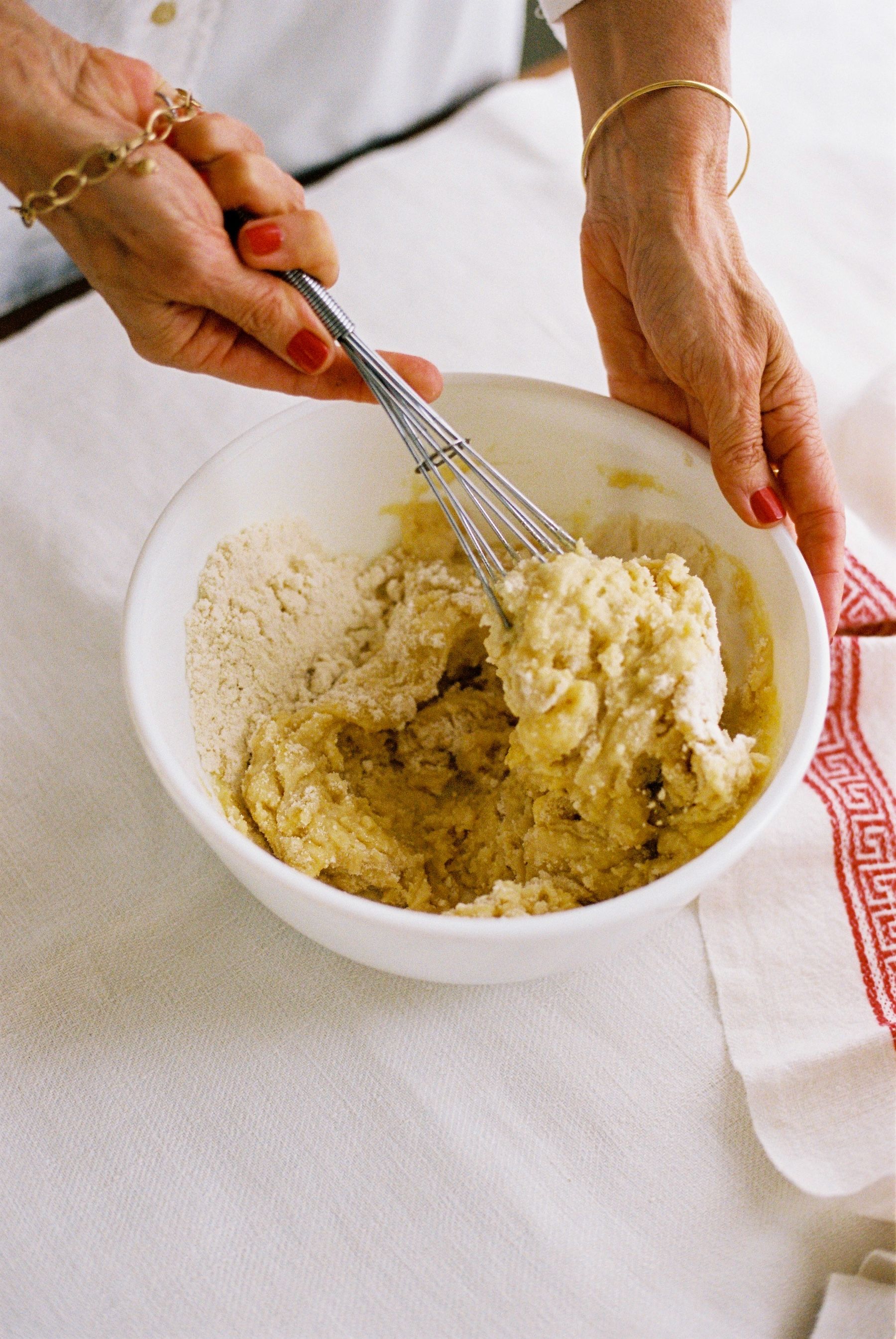 woman wearing gold bracelets mixes cake mix in a bowl  