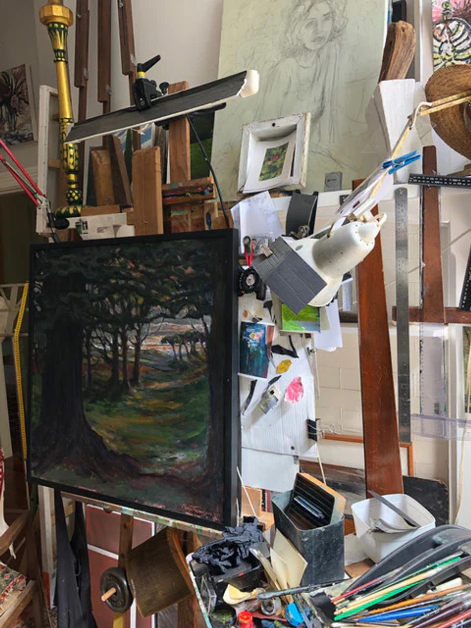 Artist's studio with tree painting on easel. Art supplies scattered around. Max Thomson's sketches and tools visible.