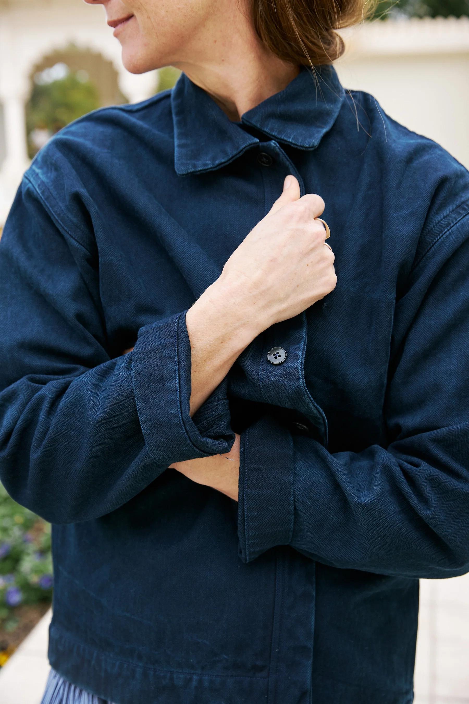 Close up of indigo jacket being wrapped around the body to show button detailing. 