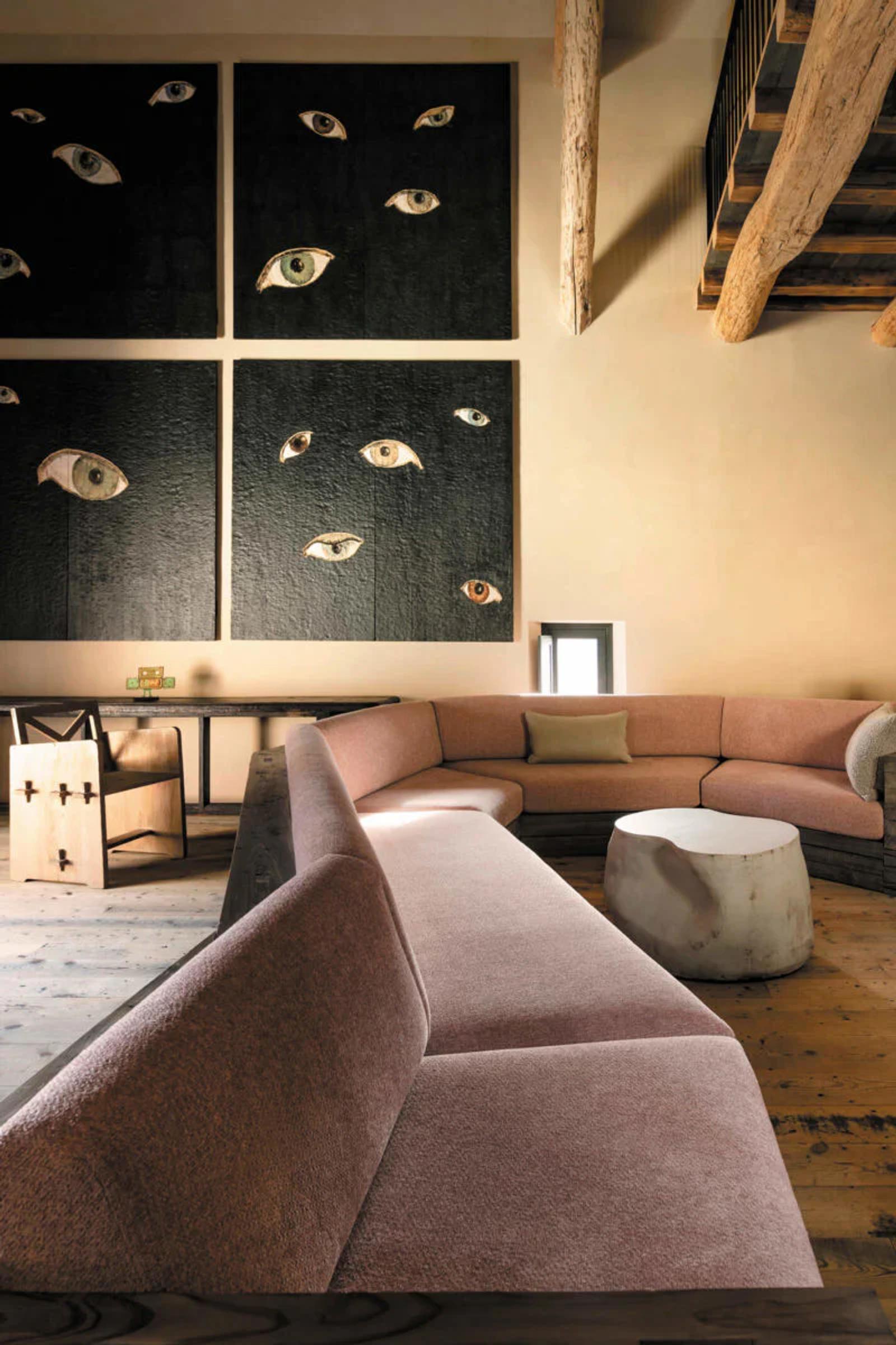 A contemporary living room with curved sofa and stone coffee table. Striking eye artwork adorns the walls, while wooden elements add warmth.