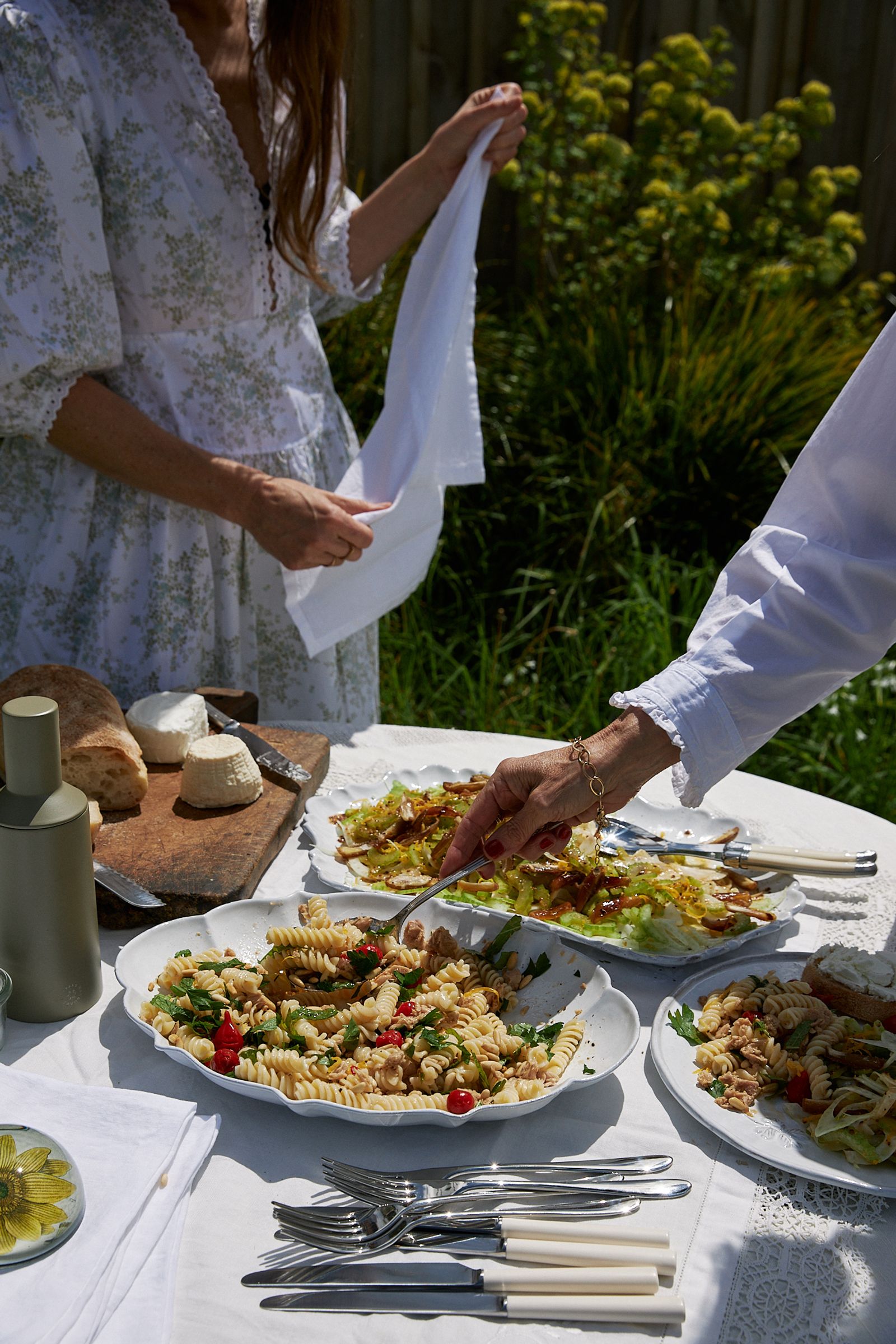 woman serves salad at an informal table in the garden