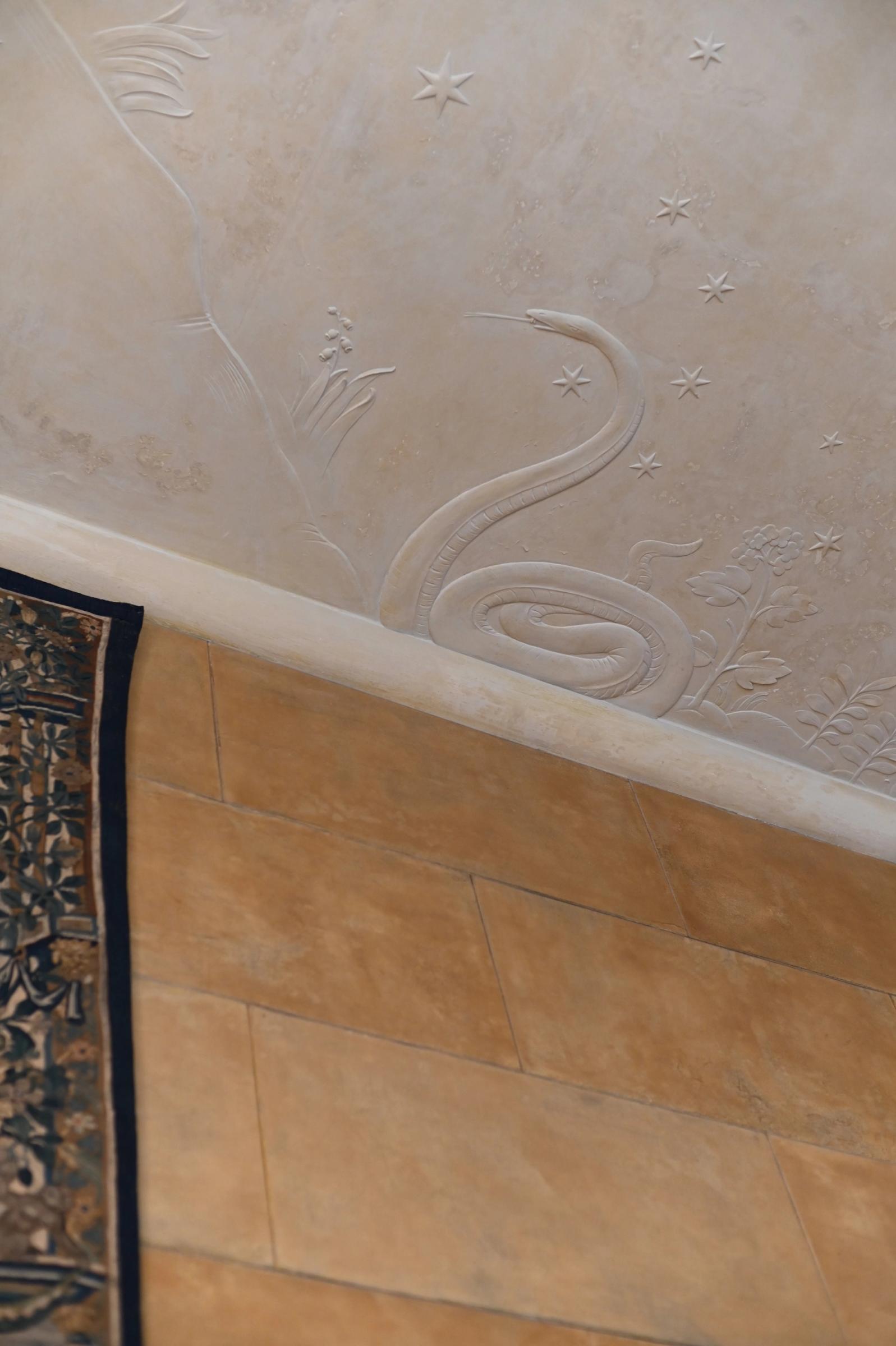 the ceiling with a carved snake next to a hung tapestry