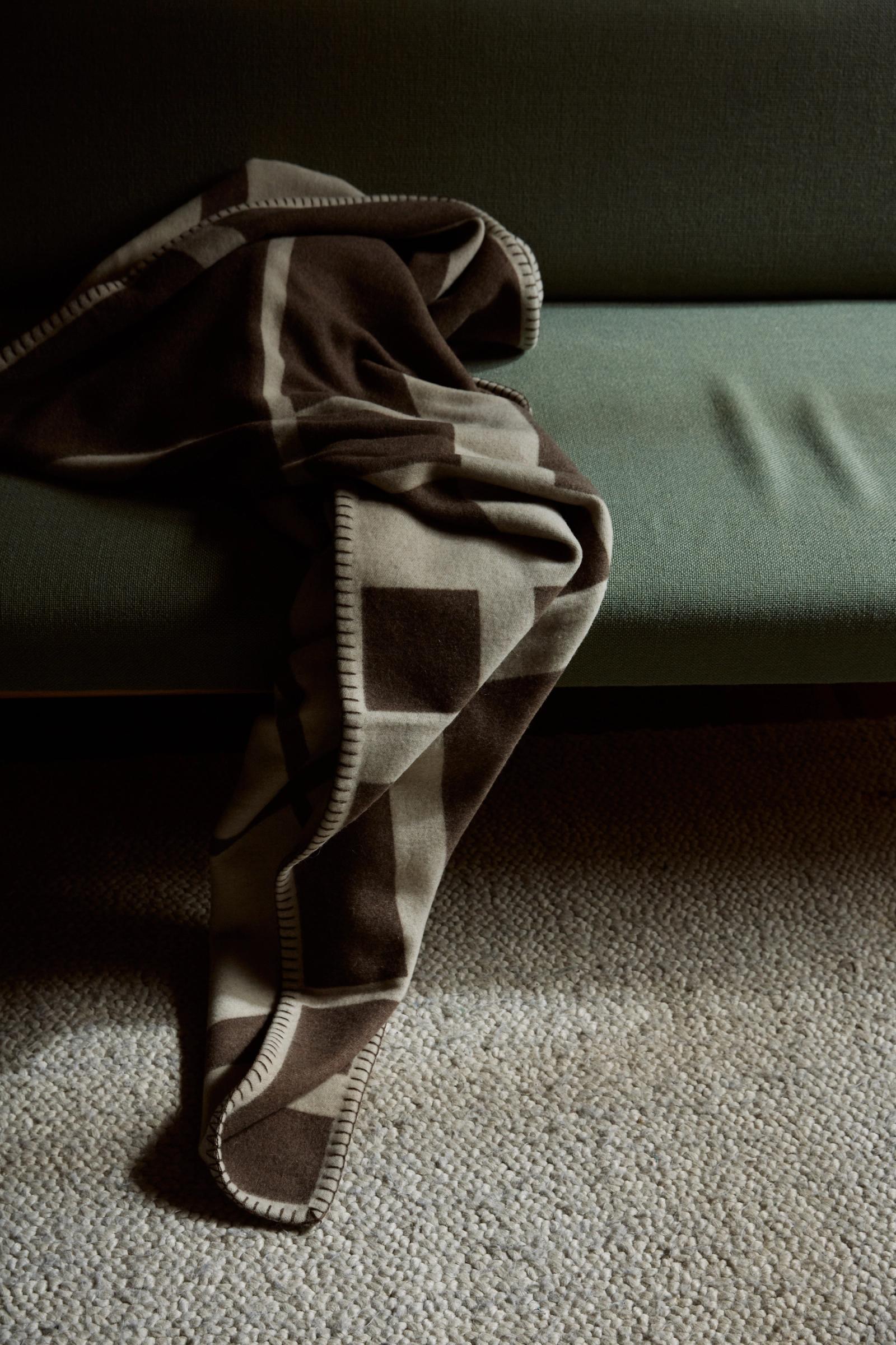 a cashmere throw is thrown over the edge of the couch and catching the sunlight on the rug below