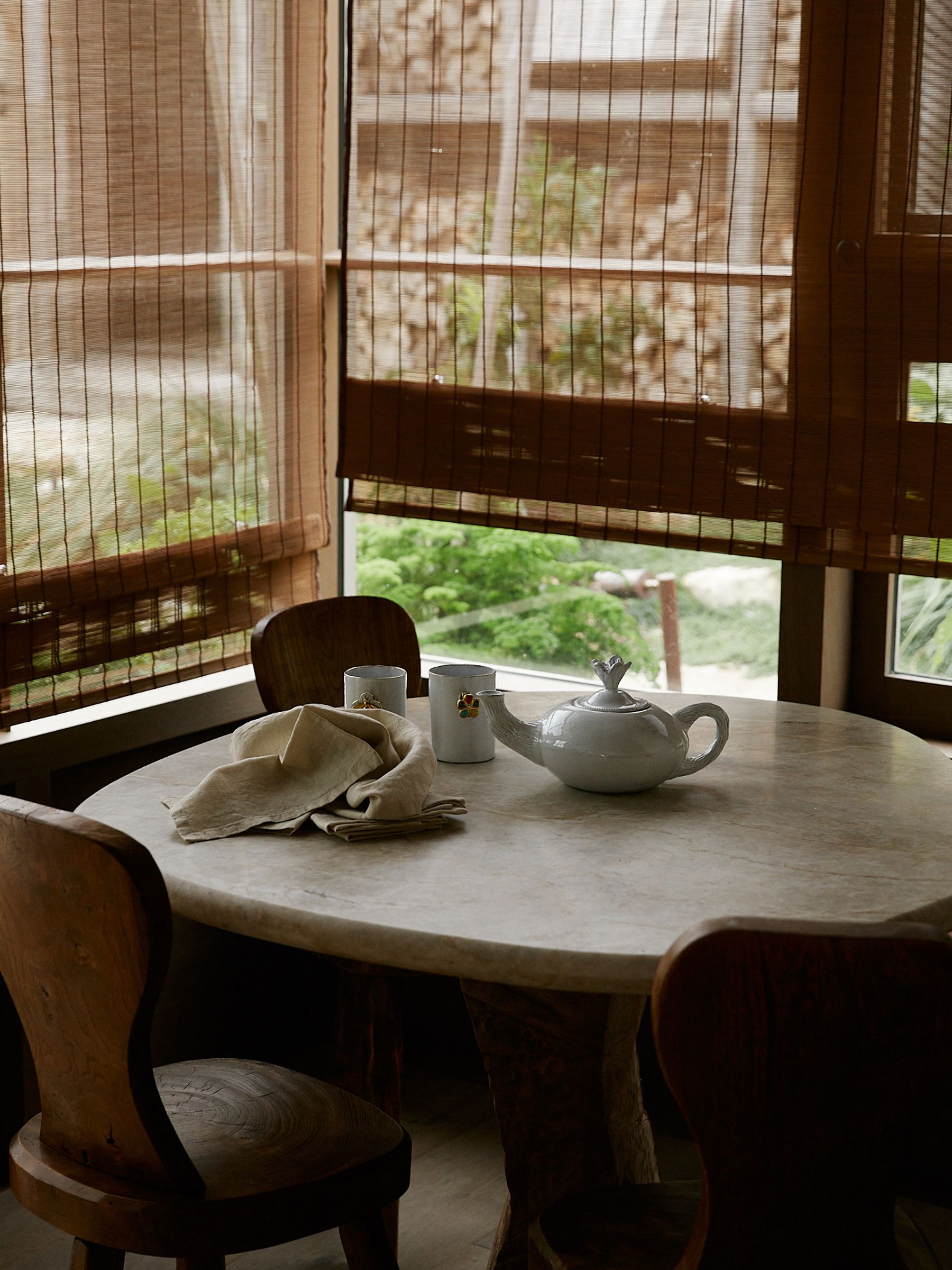 tea pot and tea cups own a round wooden table in corner of kitchen