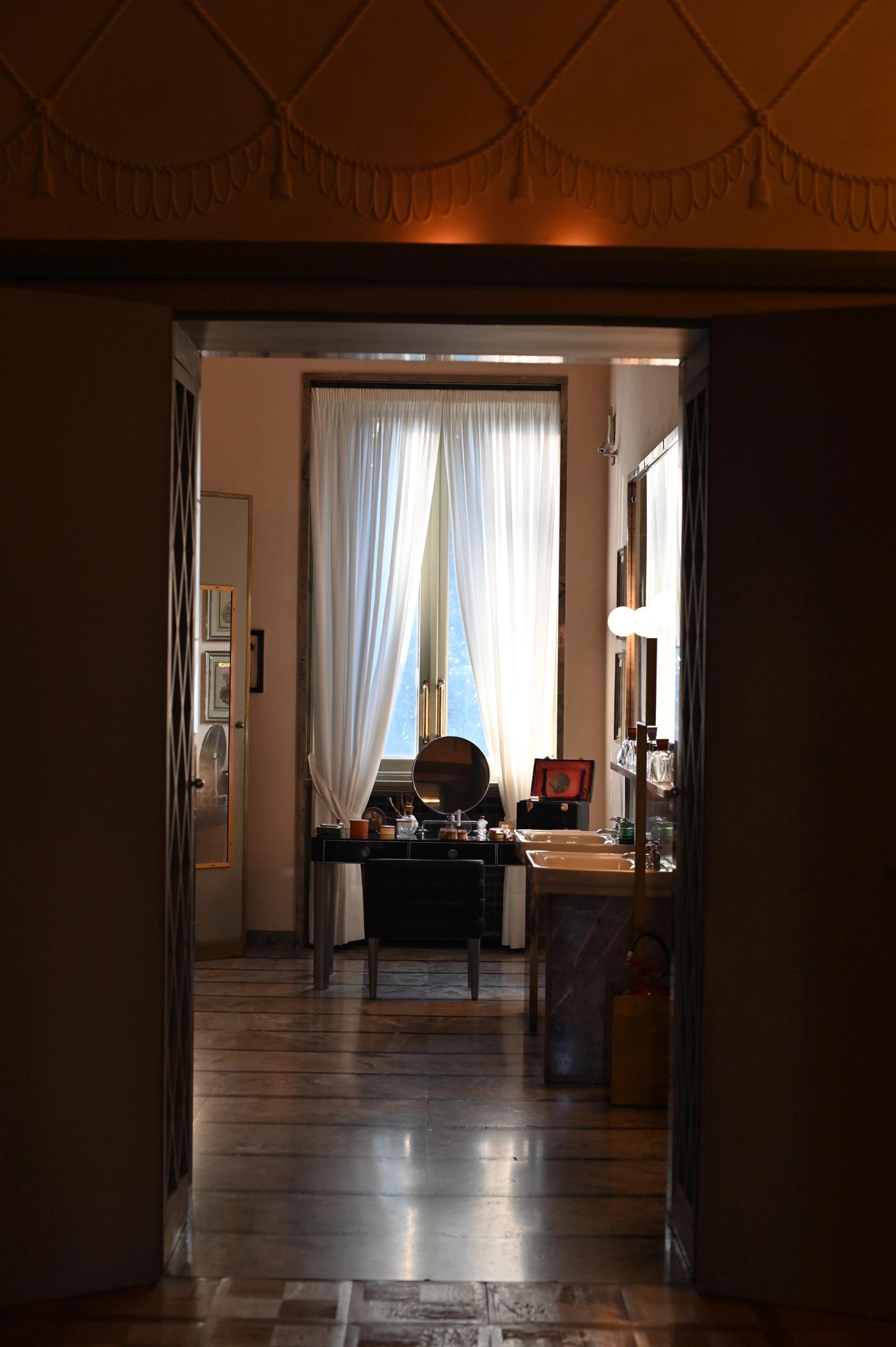 a bathroom with a mirror, white sheer curtains and marble bath