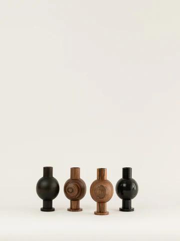 Four spherical wooden objects with cylindrical bases are arranged in a row against a light background. Each varies in colour, showcasing the craftsmanship of a New Zealand woodturning studio.