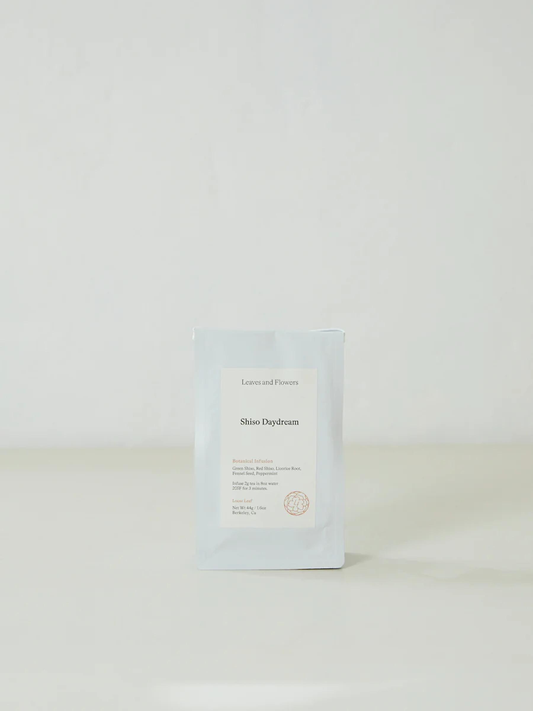 White packet labeled "Leaves and Flowers Shiso Daydream" on light surface. Simple, elegant packaging for handcrafted botanical infusions.