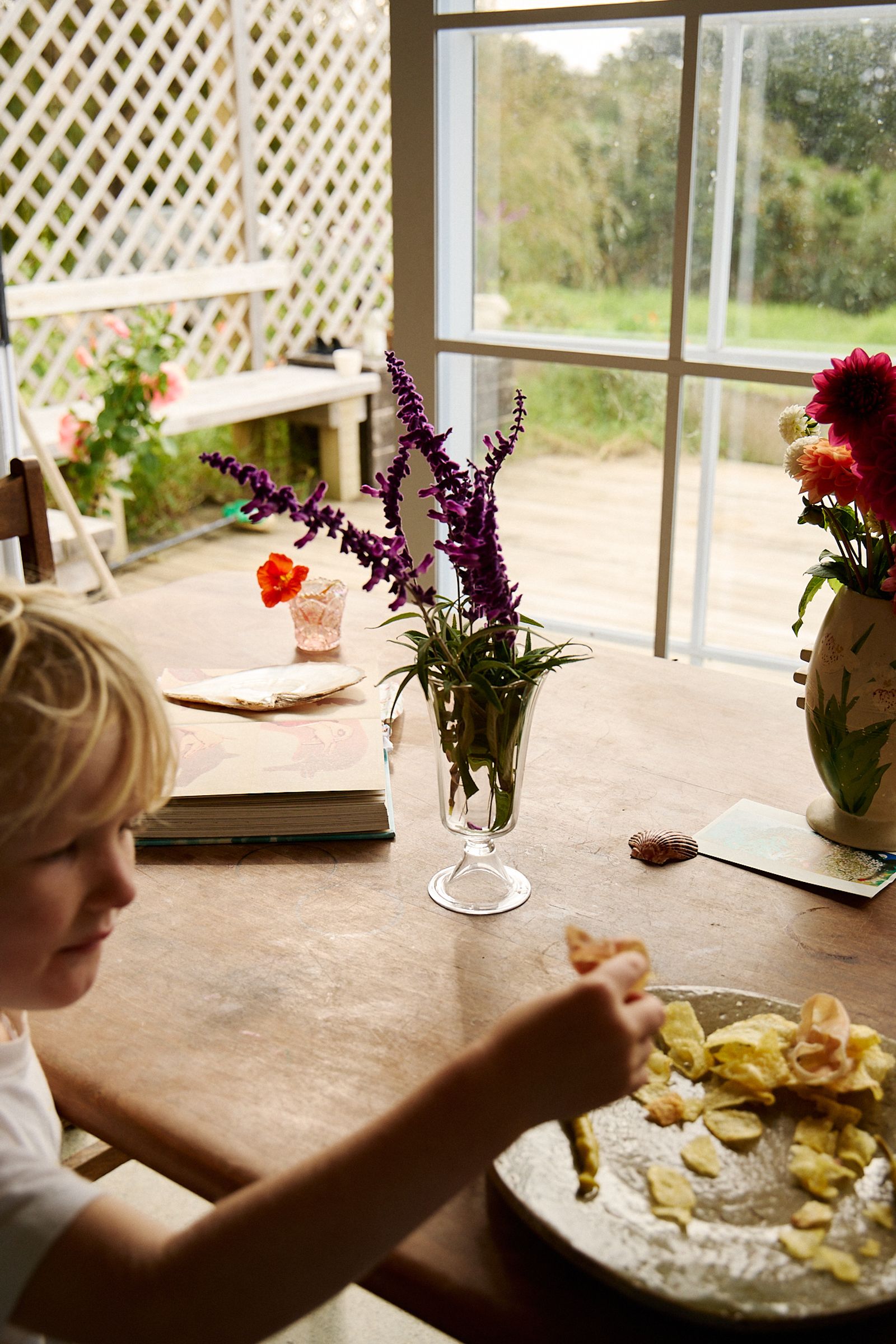 son reached for chips on a plate at dining table with vase of flowers 