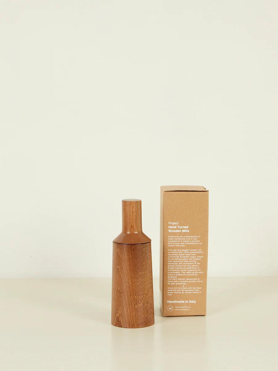 Wooden pepper grinder next to brown packaging box. Light wood finish contrasts with minimalistic, text-heavy label.