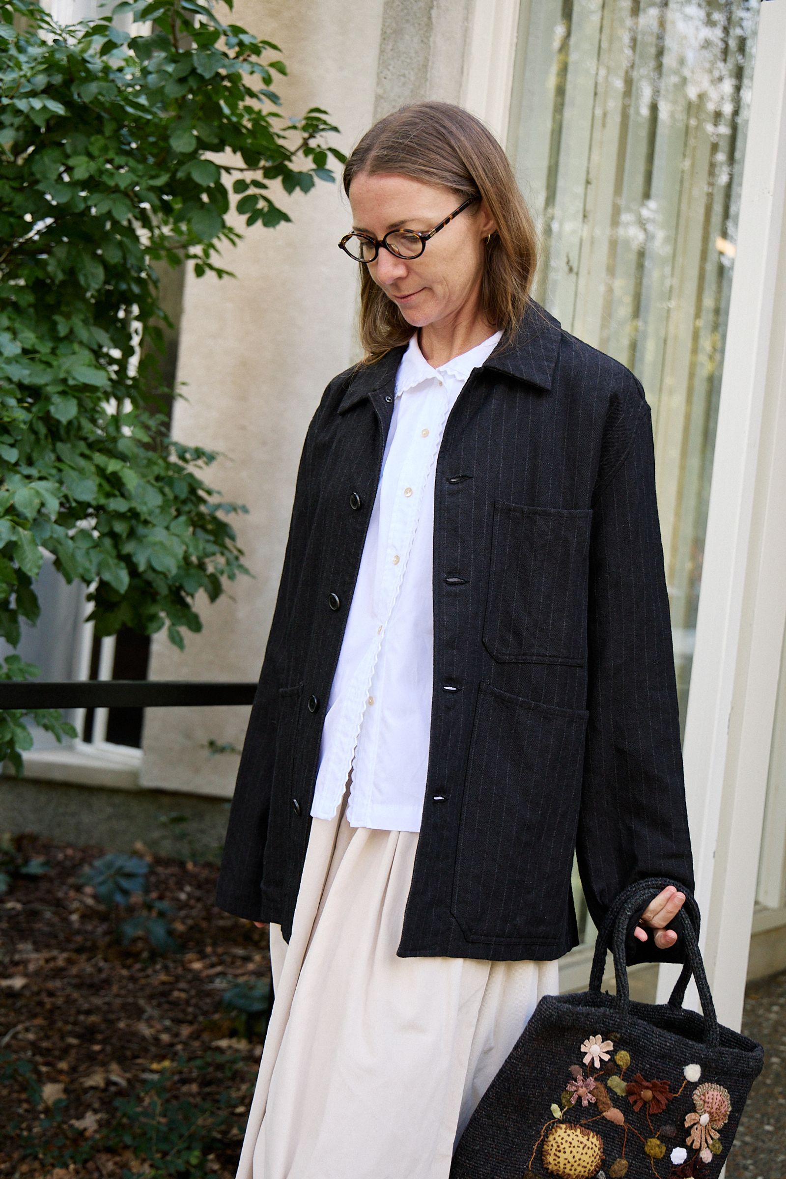 black jacket over white crisp shirt and soft cord skirt with textured tote bag