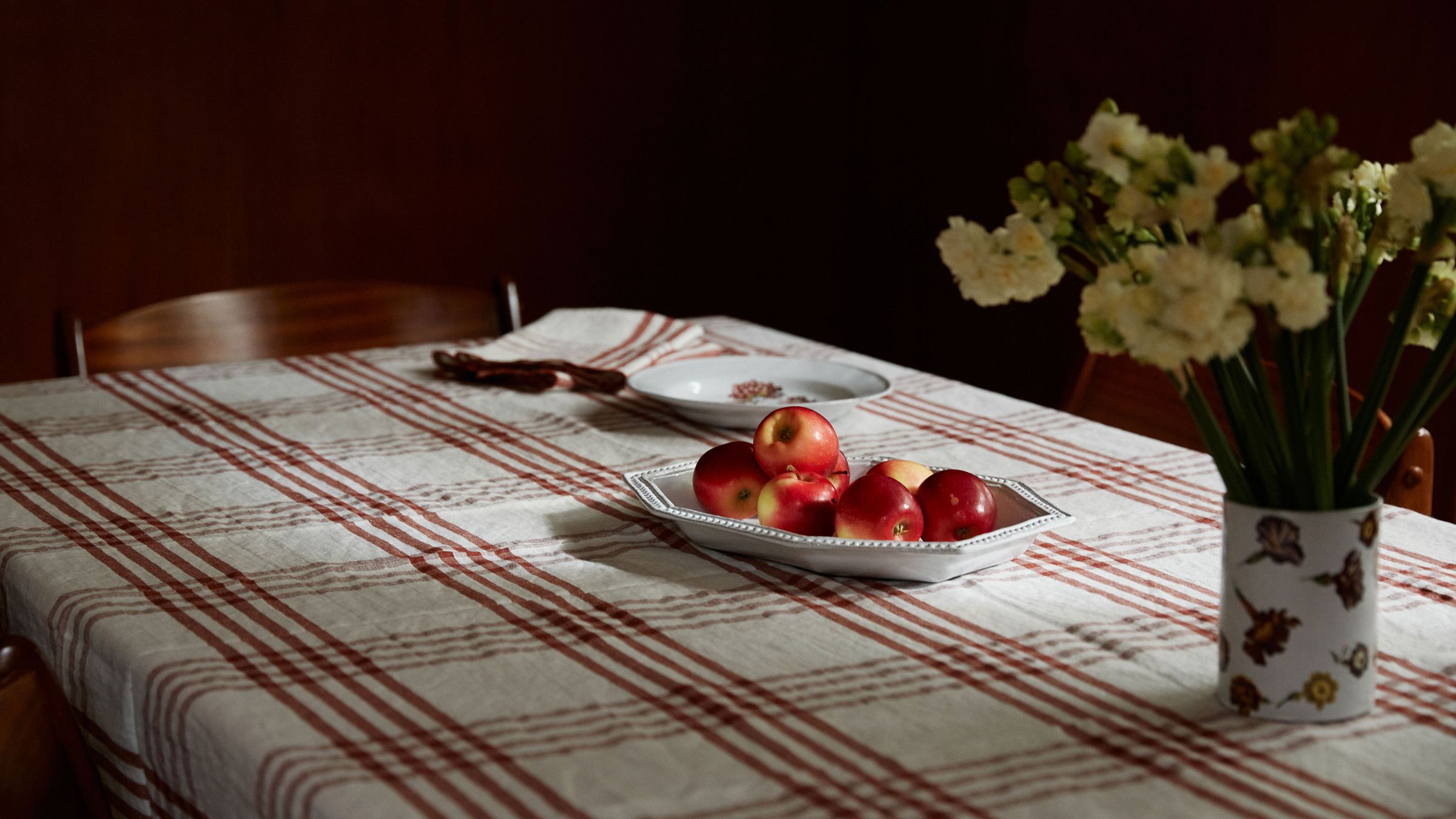 Check table cloth with flowers and a plate of red apples