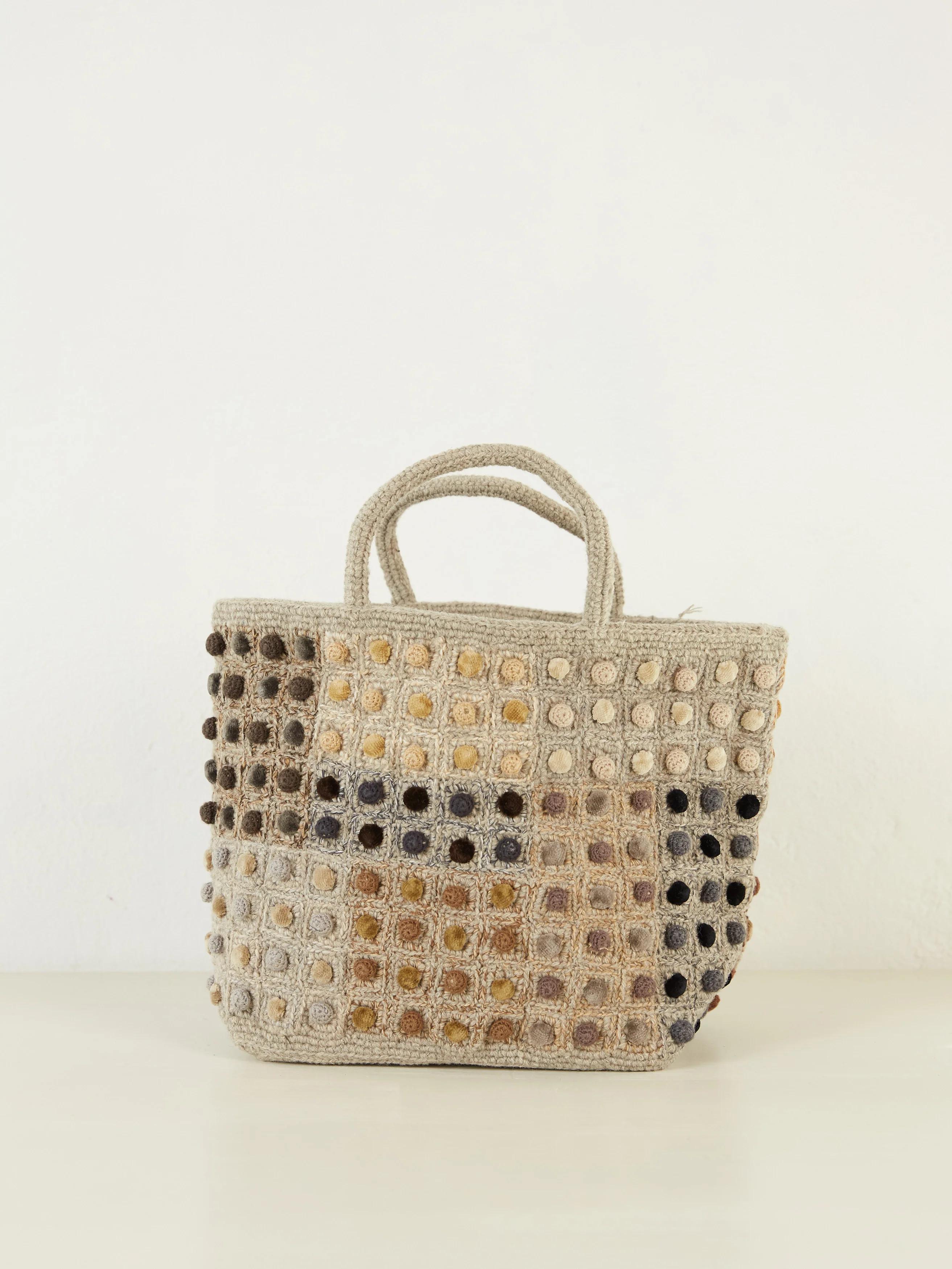 A crochet tote bag by Sophie Digard, featuring a checkered bauble pattern in beige, brown, and black, with short handles.