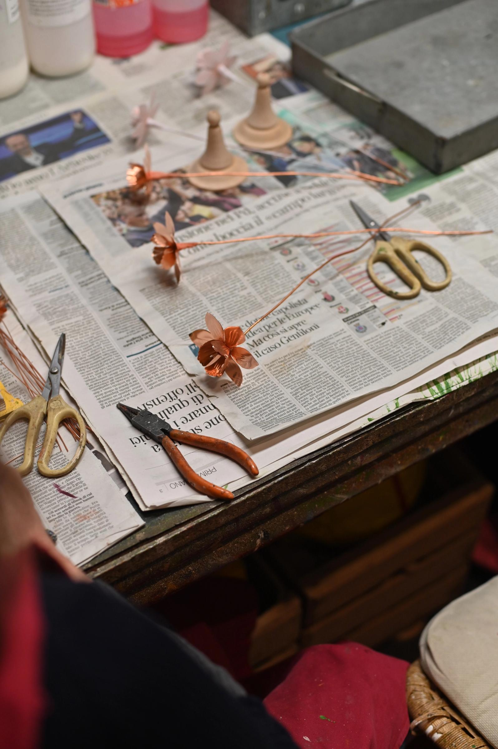 copper flowers on top of newspaper covered workbench