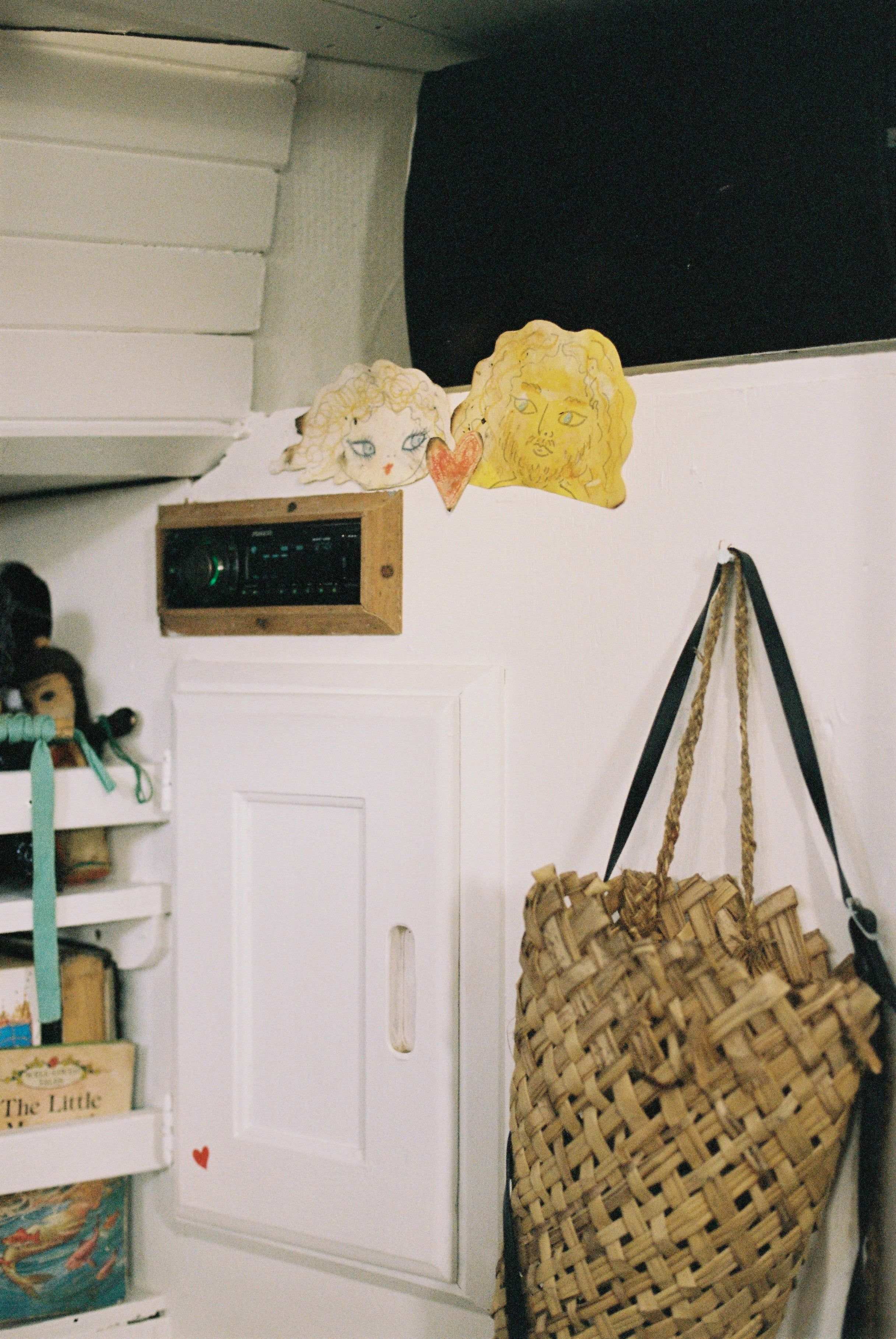 Children's drawings on wall above vent. White door below, woven basket on hook, bookshelves visible.