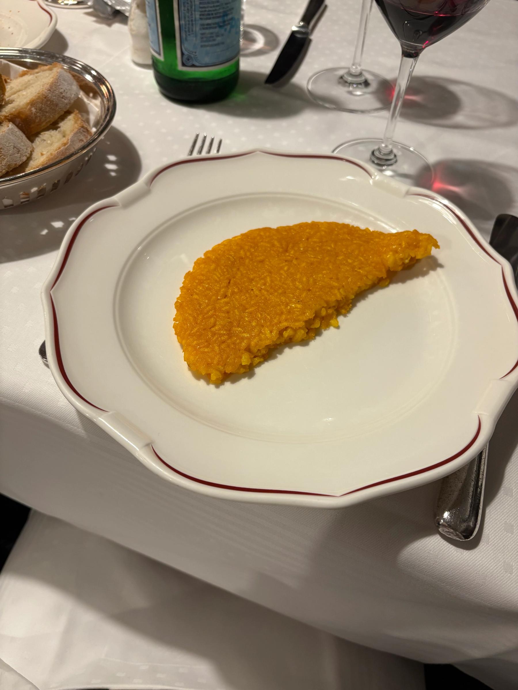 a crispy slab of baked risotto sits on a bistro plate