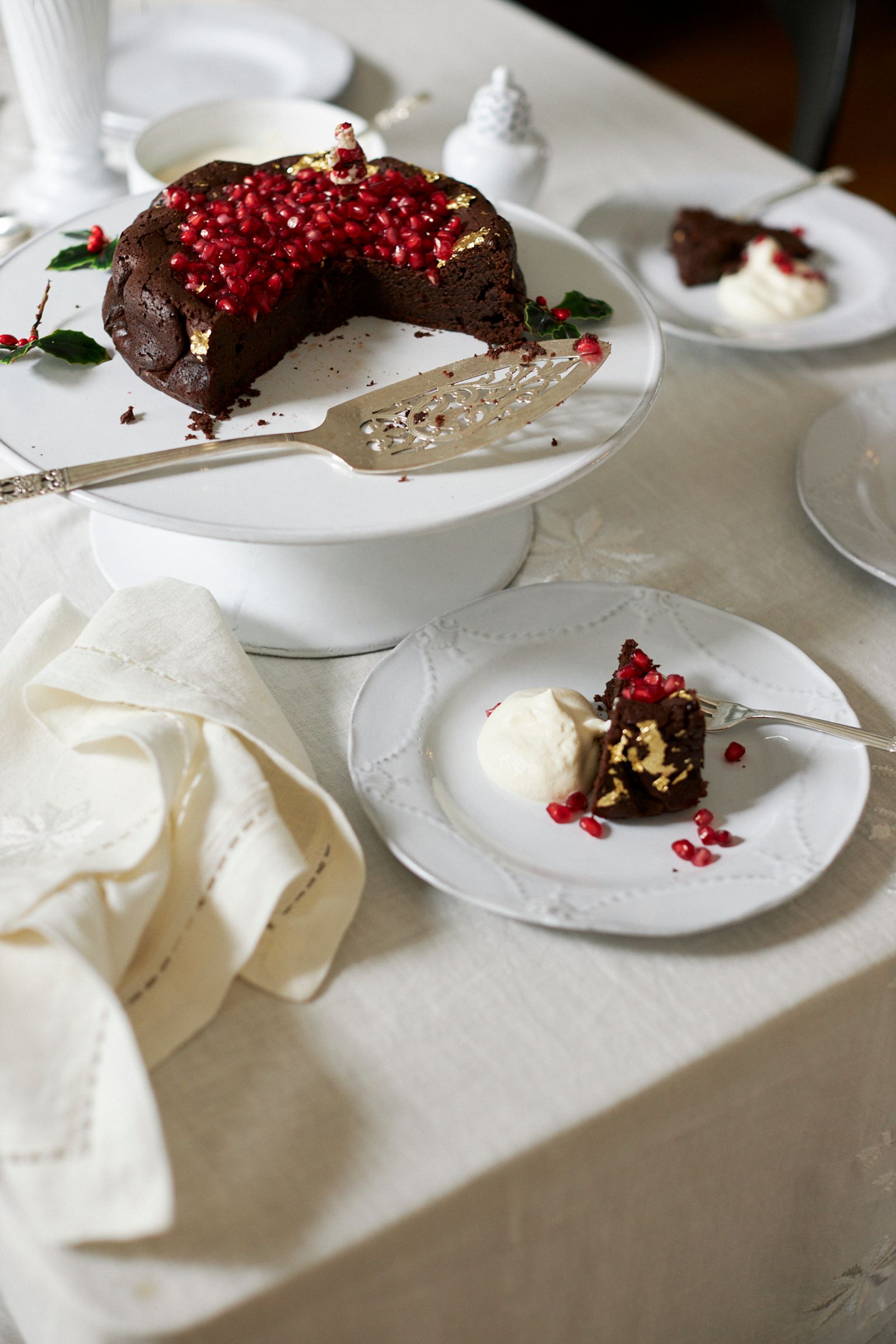 chocolate cake is served off a cake stand and only a white plate with cream