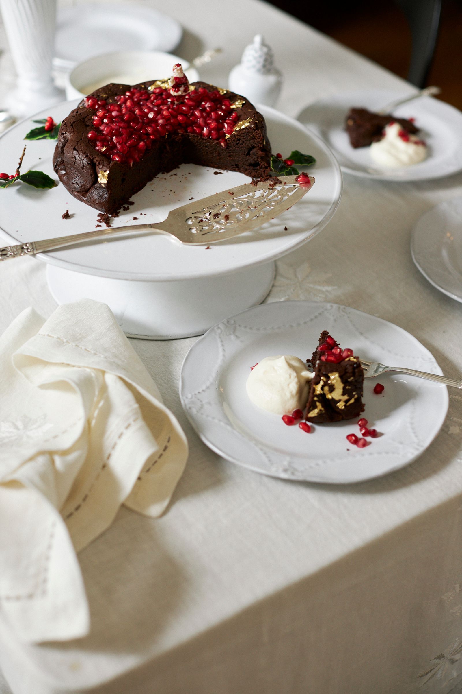 chocolate cake is served off a cake stand and only a white plate with cream